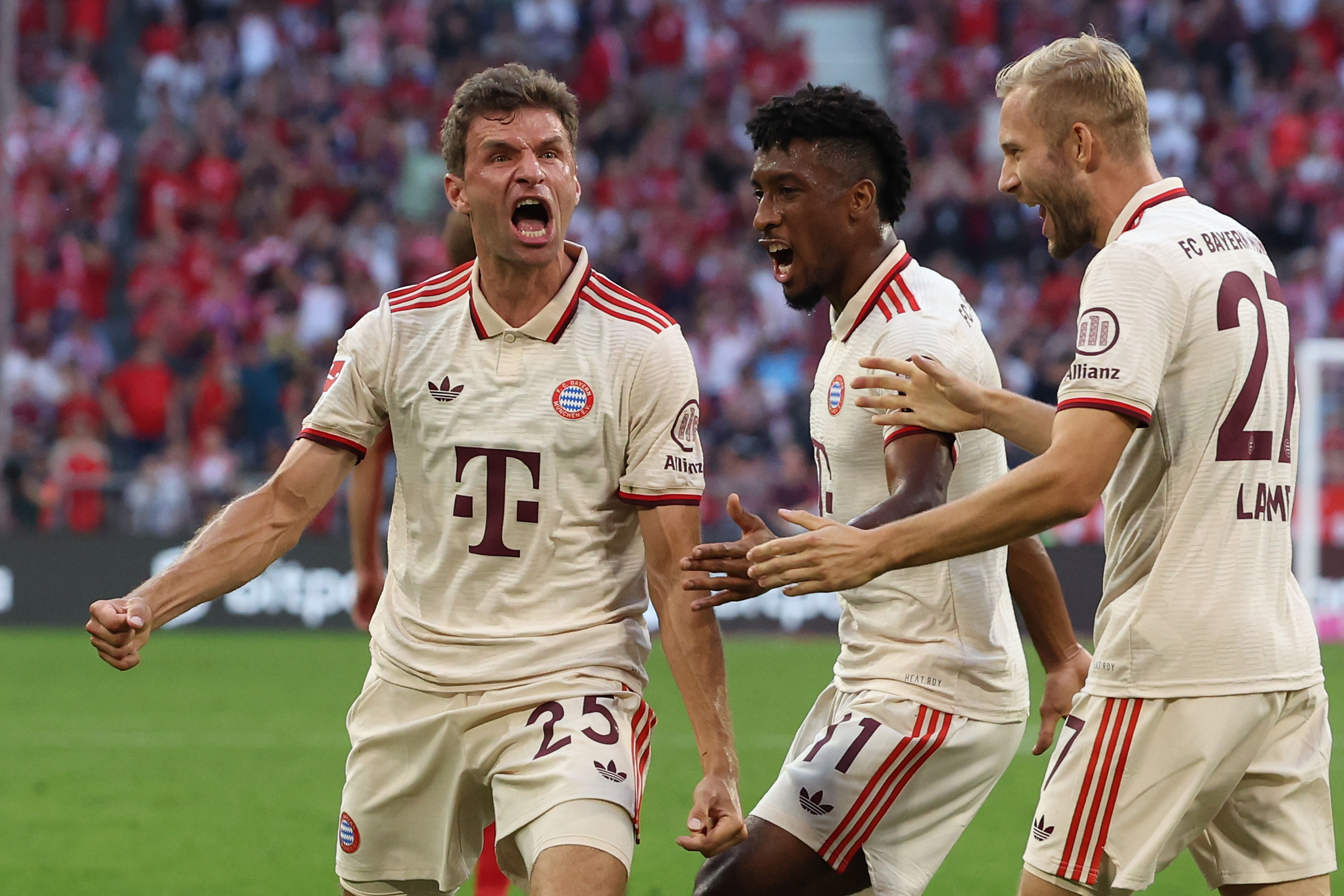 Drei Bayern-Spieler jubeln ausgelassen nach einem Tor im Fußballstadion.