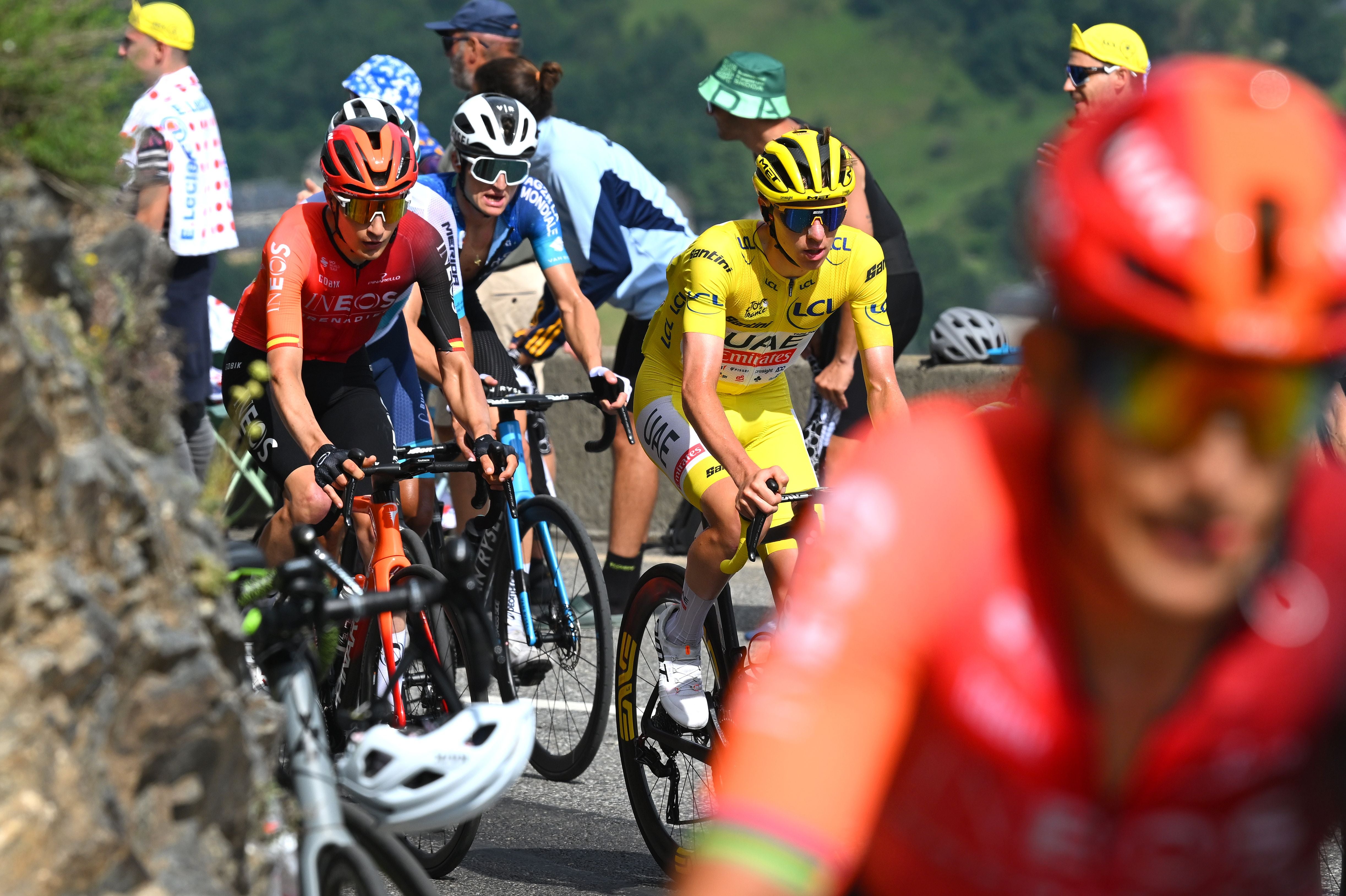 Radrennfahrer kämpfen bei der Tour de France 2024 bergauf, Zuschauer verfolgen am Straßenrand.