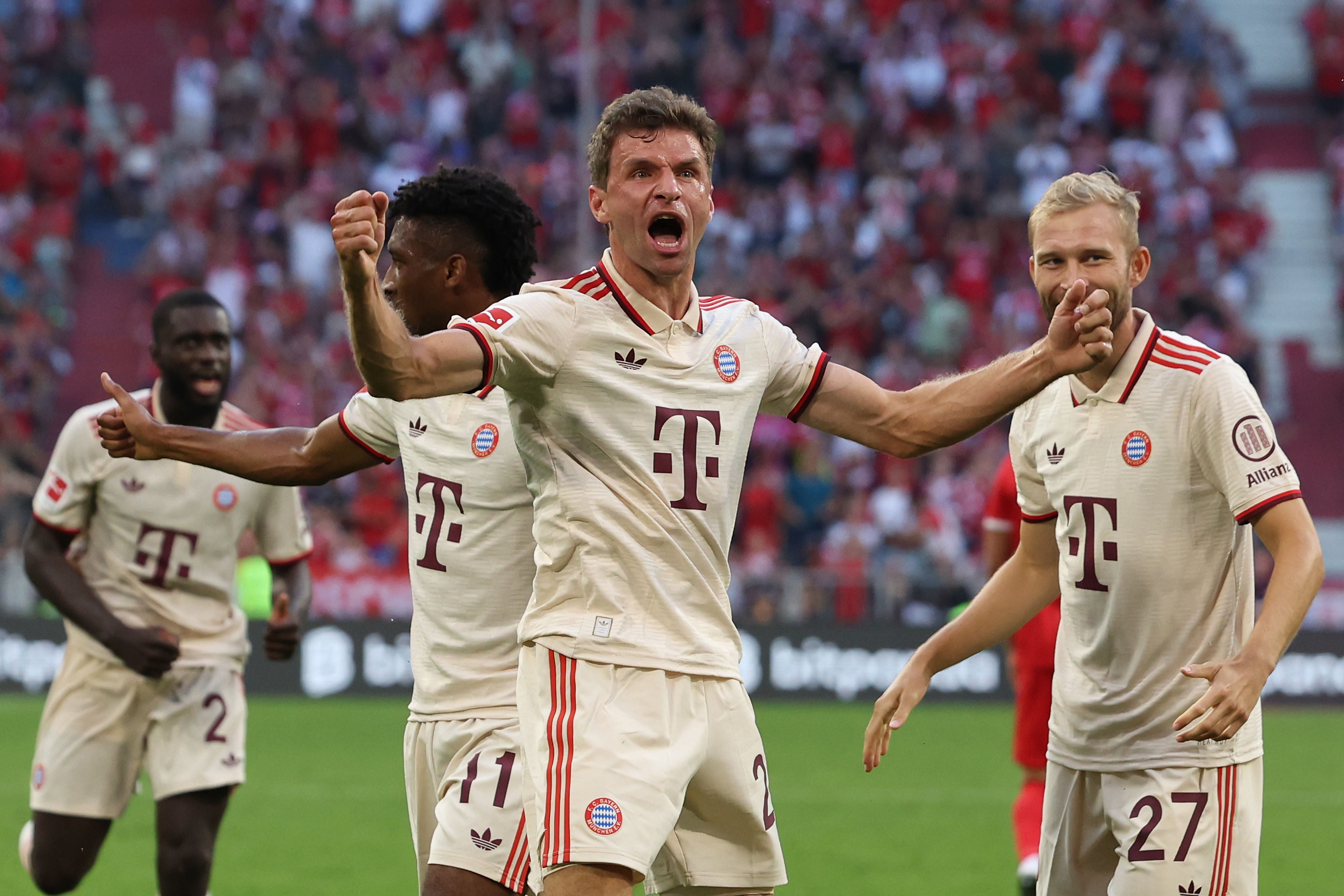 Jubelnde Bayern-Spieler im cremefarbenen Trikot nach einem Tor im Fußballstadion.