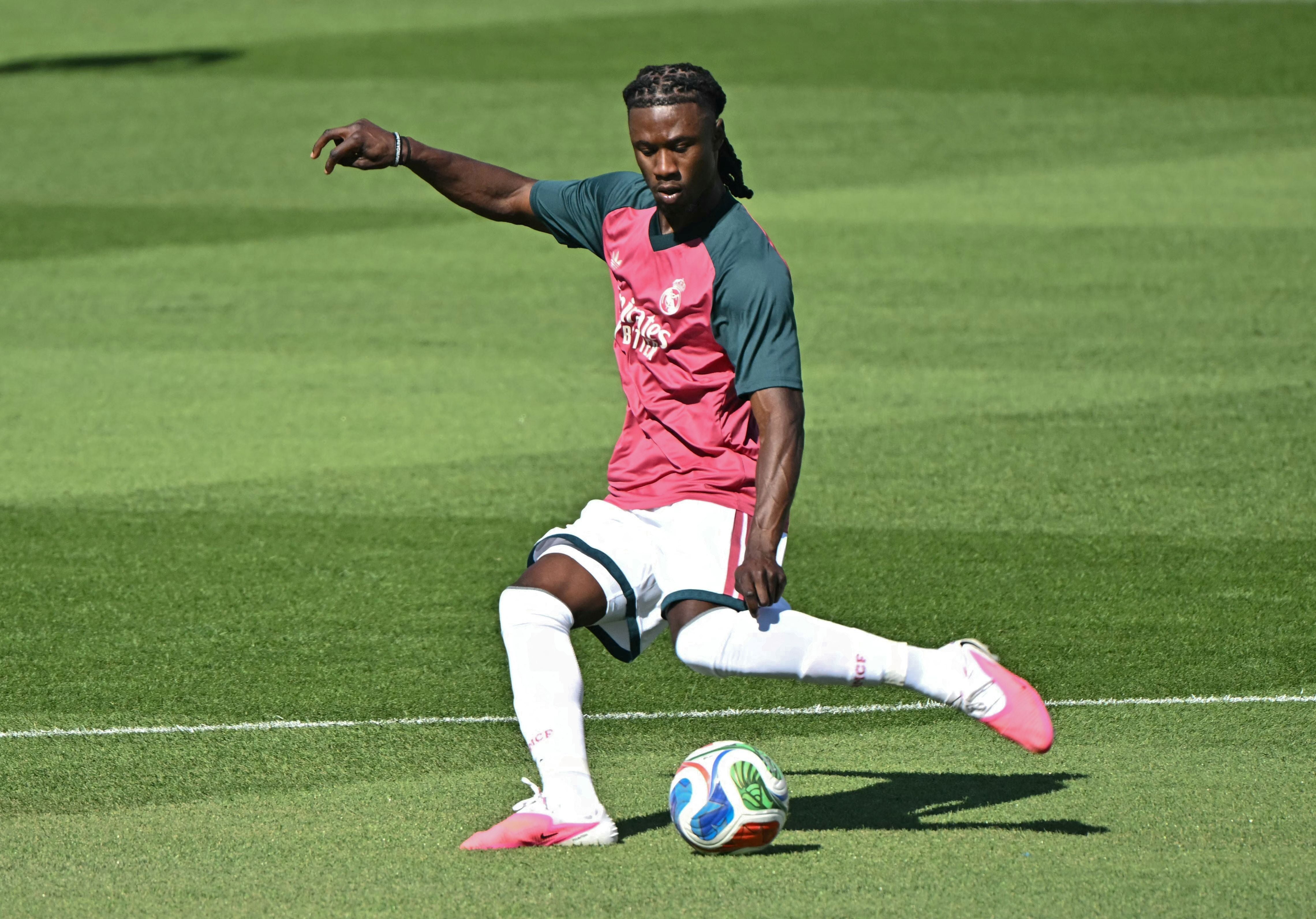 Ein Fußballspieler von Real Madrid trainiert auf einem grünen Rasenplatz und spielt den Ball.