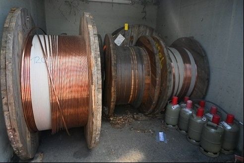 Große Kabelrollen und mehrere Gasflaschen stehen nebeneinander in einem Betonraum.