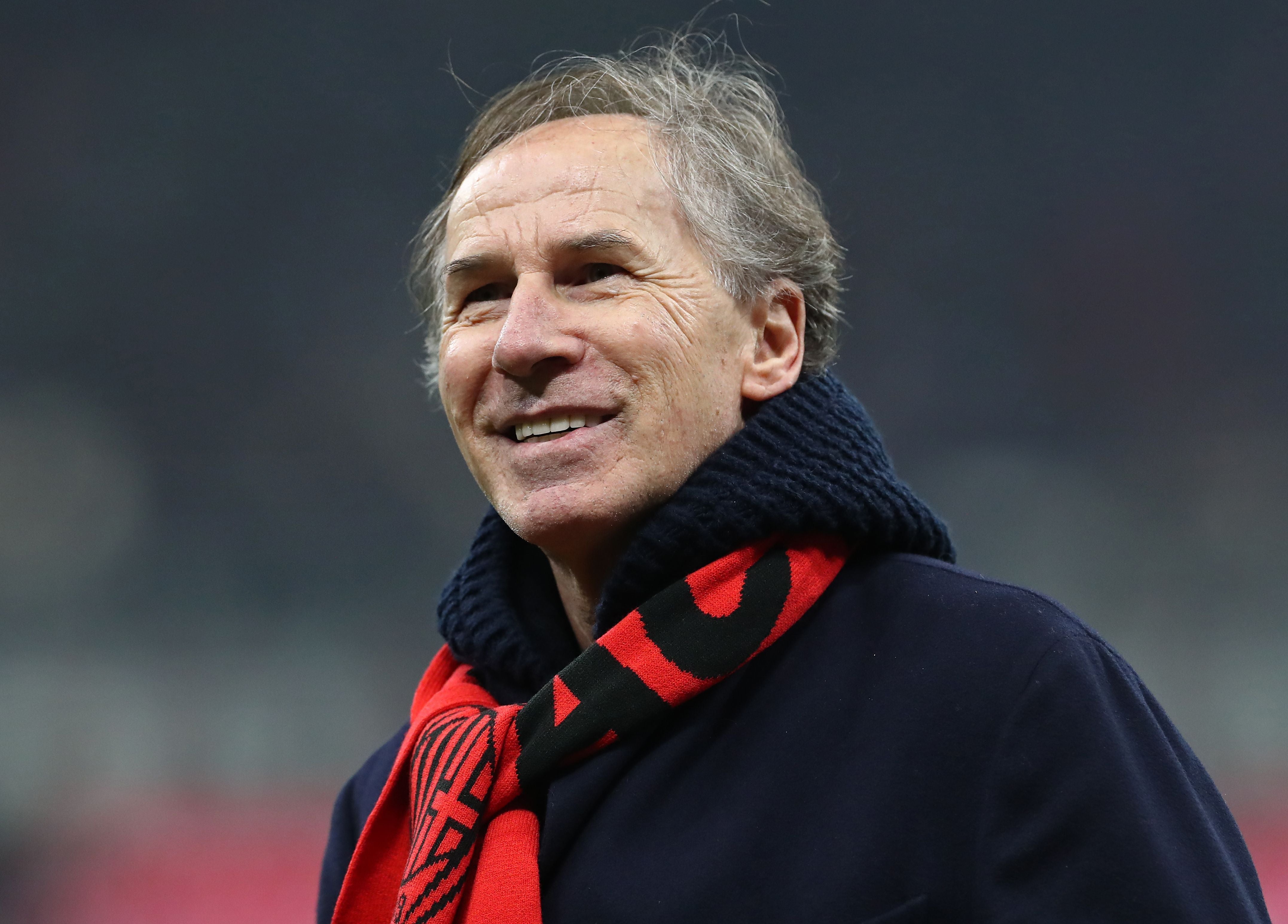 Ein lächelnder Mann mit Schal steht im Stadion vor unscharfem Hintergrund.