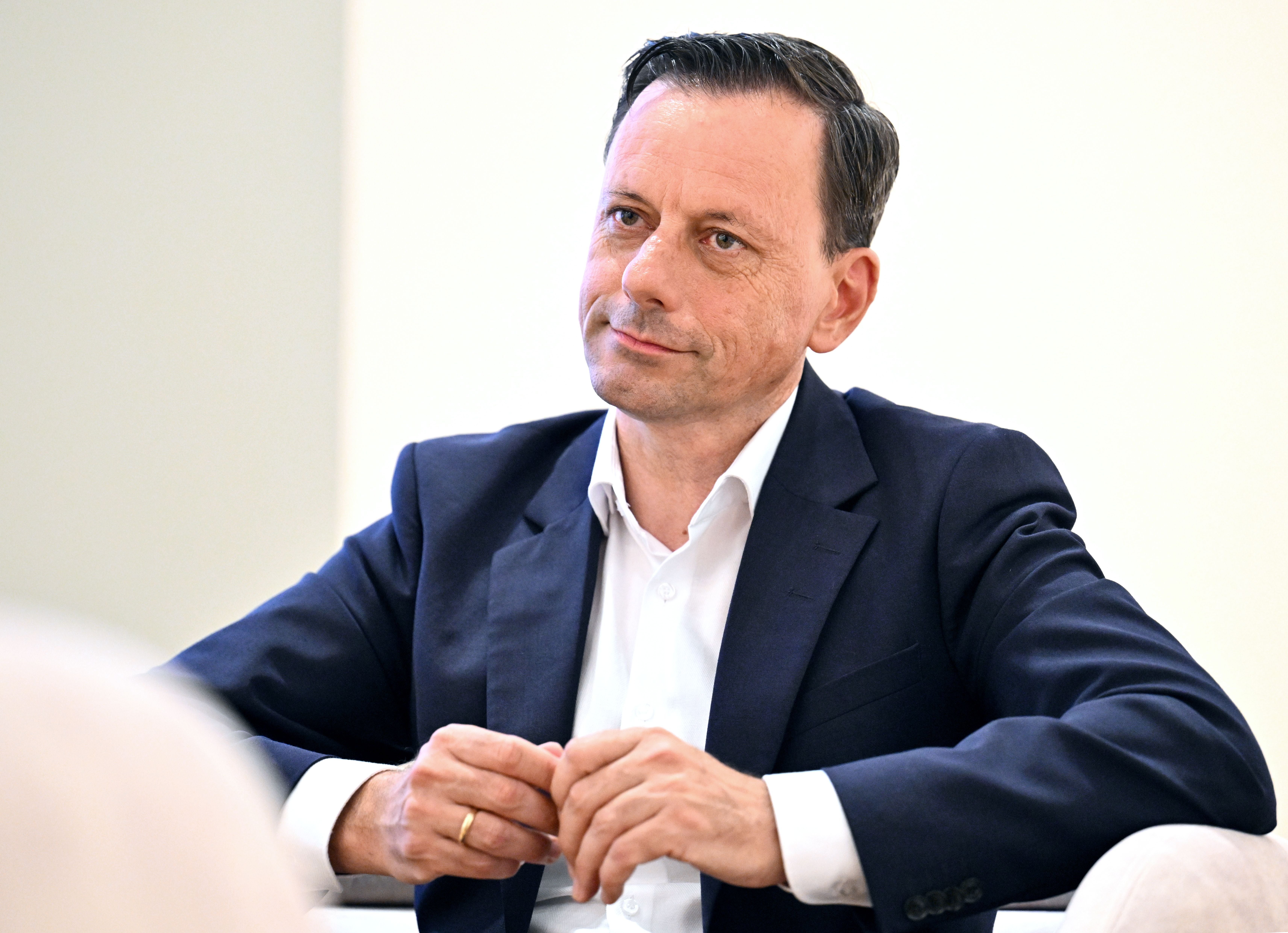 Mann im Anzug sitzt bei einem Interview und blickt aufmerksam nach vorne.