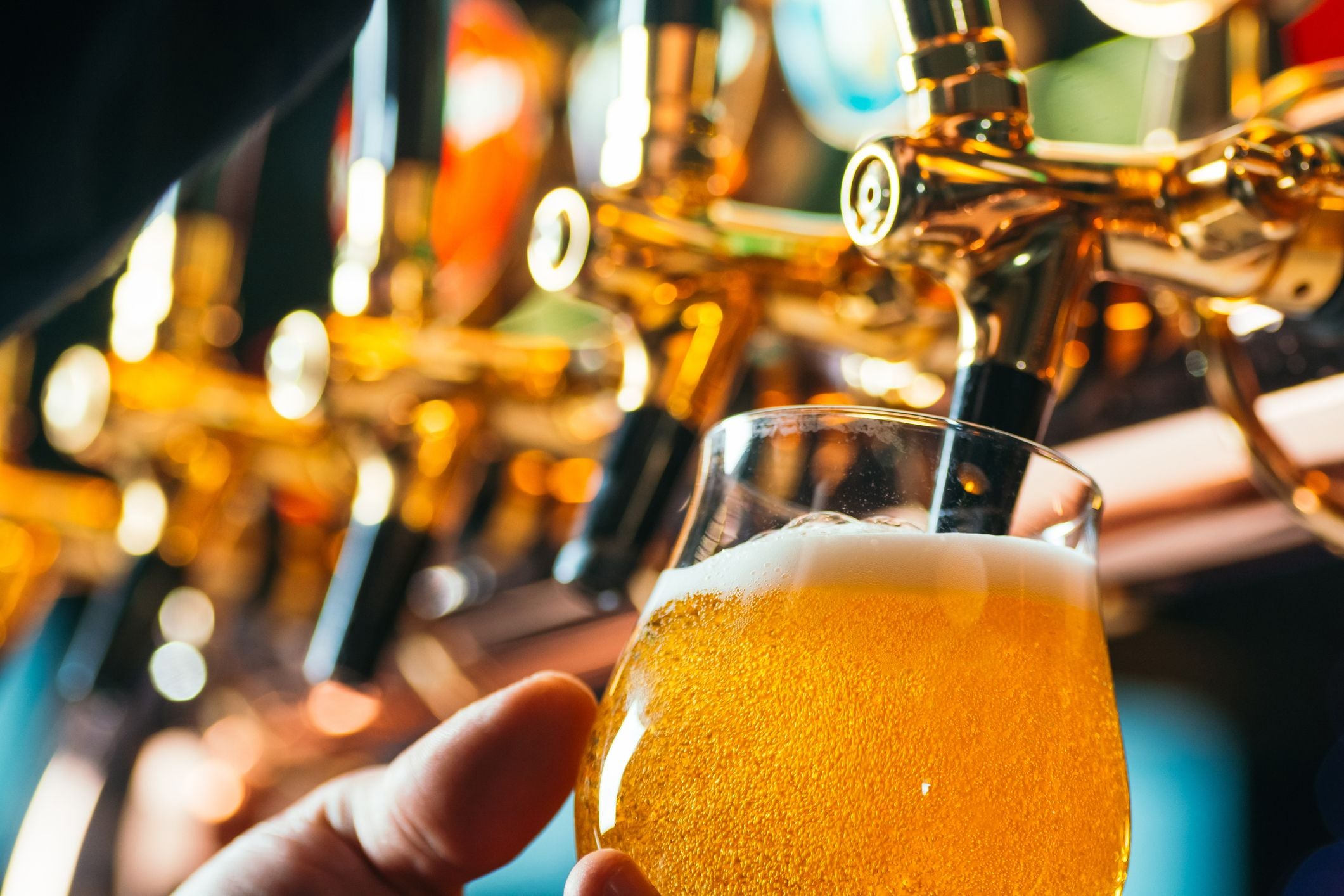 Nahaufnahme eines Bieres, das vom Zapfhahn in ein Glas in einer Bar eingeschenkt wird.