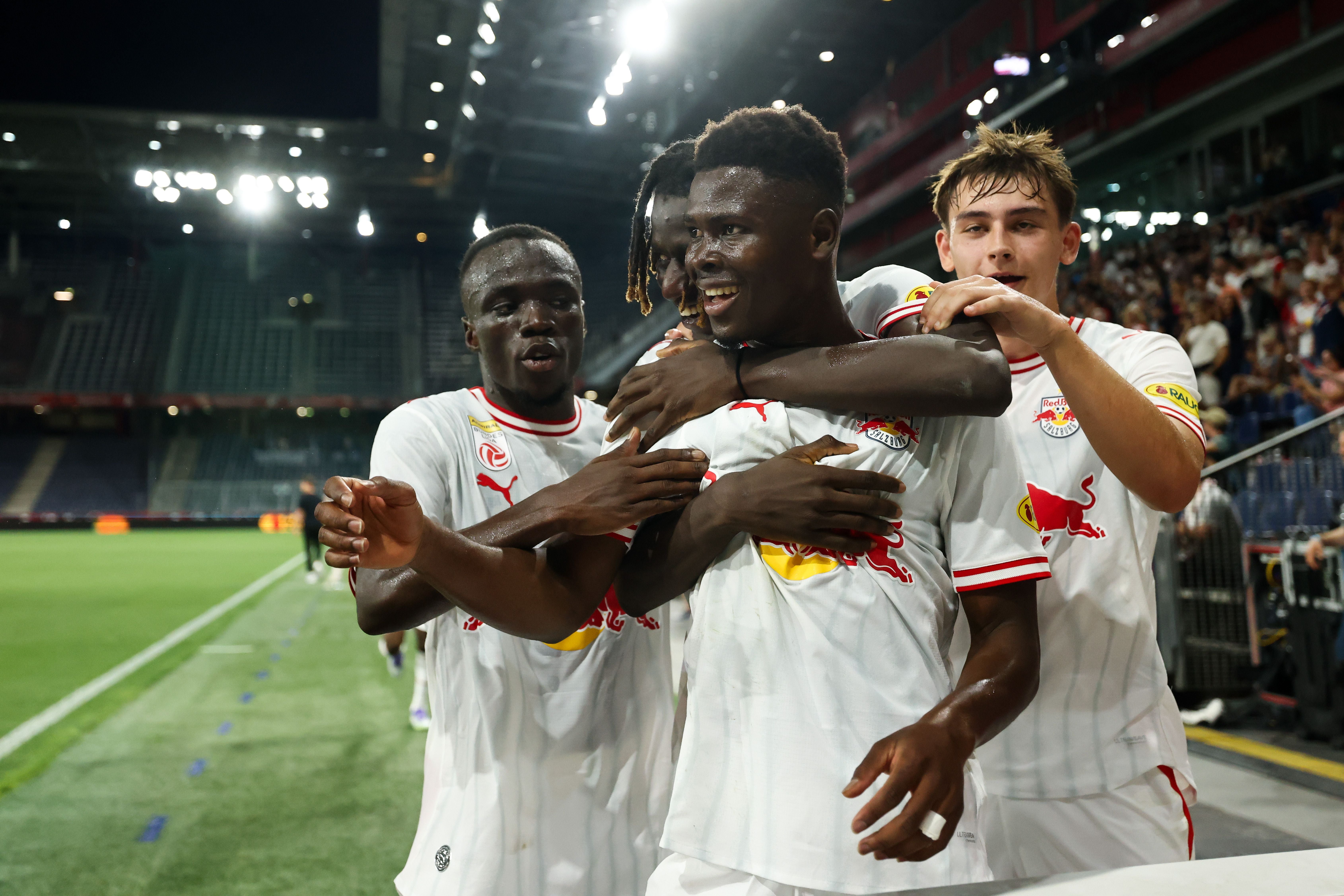 Vier Fußballspieler von Red Bull Salzburg jubeln gemeinsam nach einem Tor im Stadion.