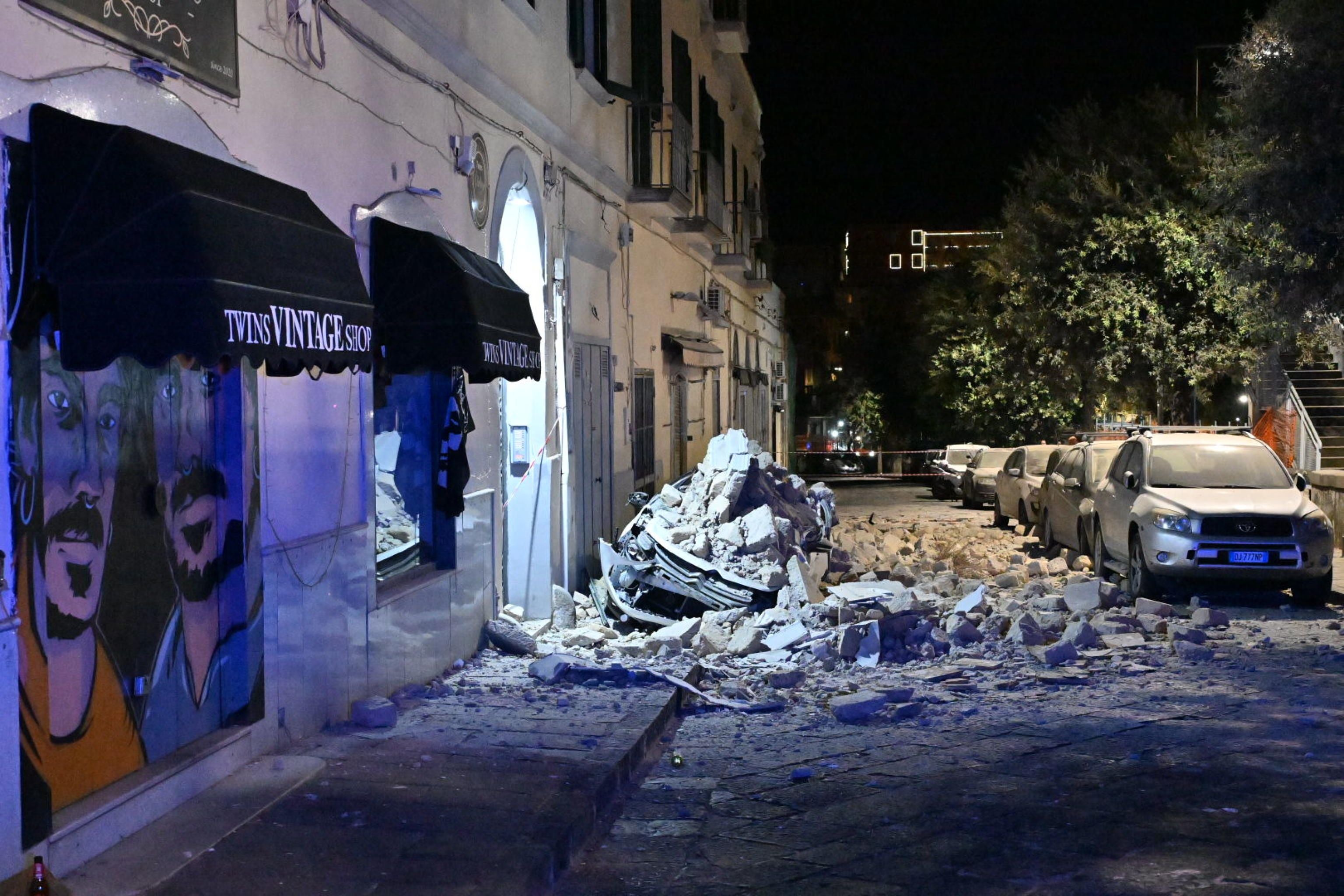 Trümmer und beschädigte Autos auf einer Straße nach einem Erdbeben in Pozzuoli bei Nacht.