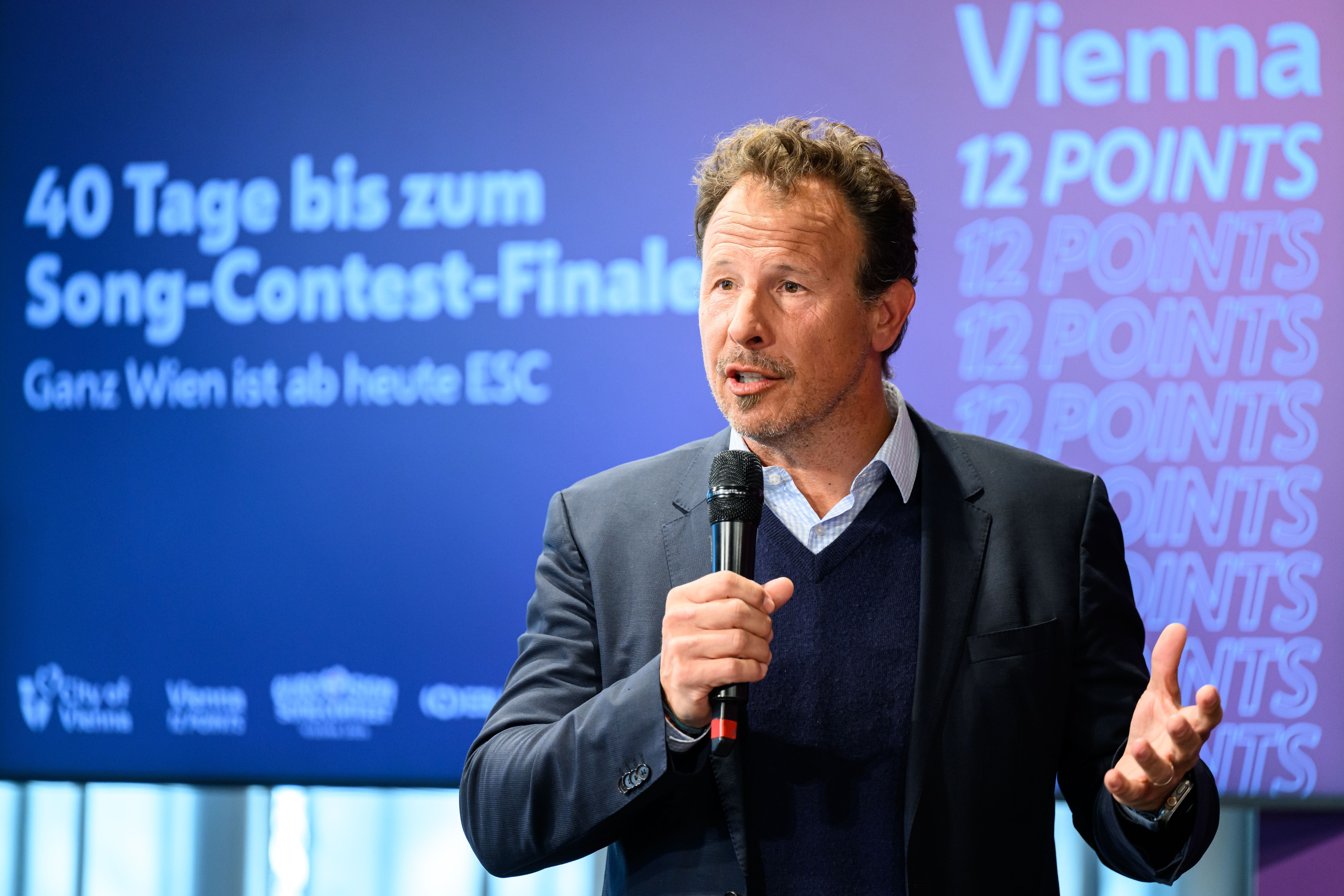 Ein Mann spricht mit Mikrofon bei einer Präsentation zum Eurovision Song Contest in Wien.