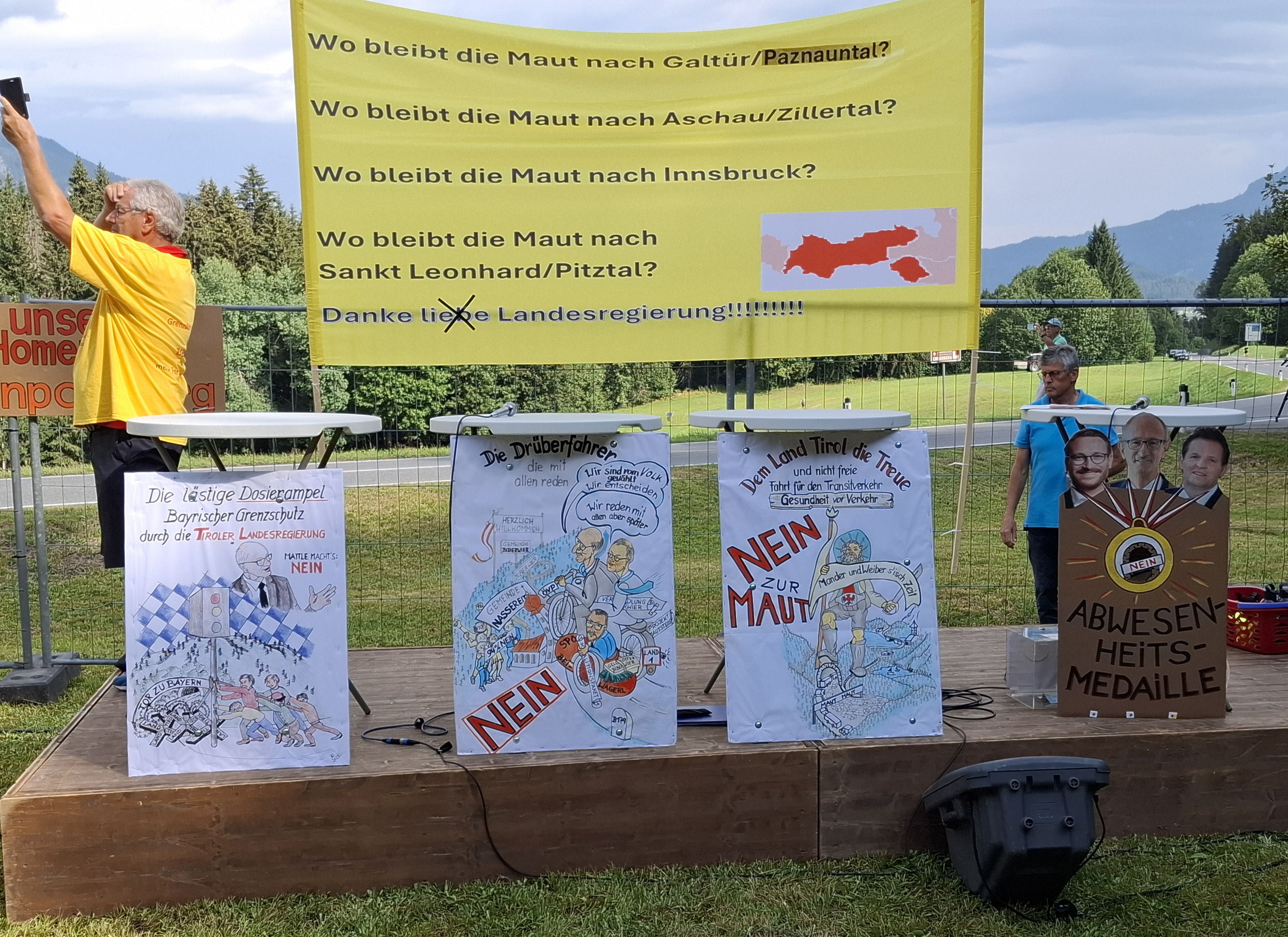 Transparente und Plakate mit Forderungen gegen die Maut auf einer Bühne bei einer Demonstration in Reutte.