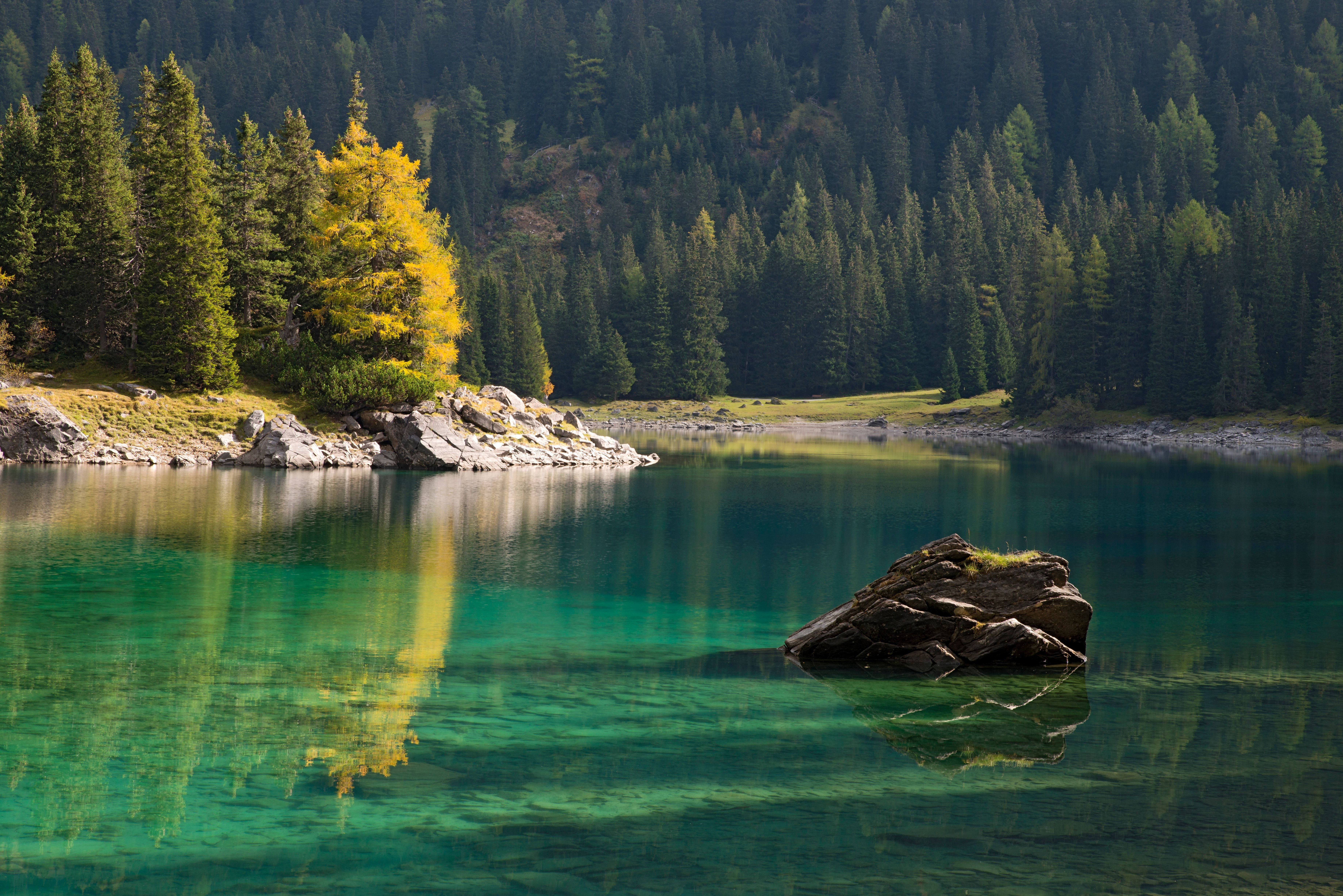 Klarer Bergsee mit Felsen und Nadelwald am Ufer in Obernberg am Brenner, Tirol.