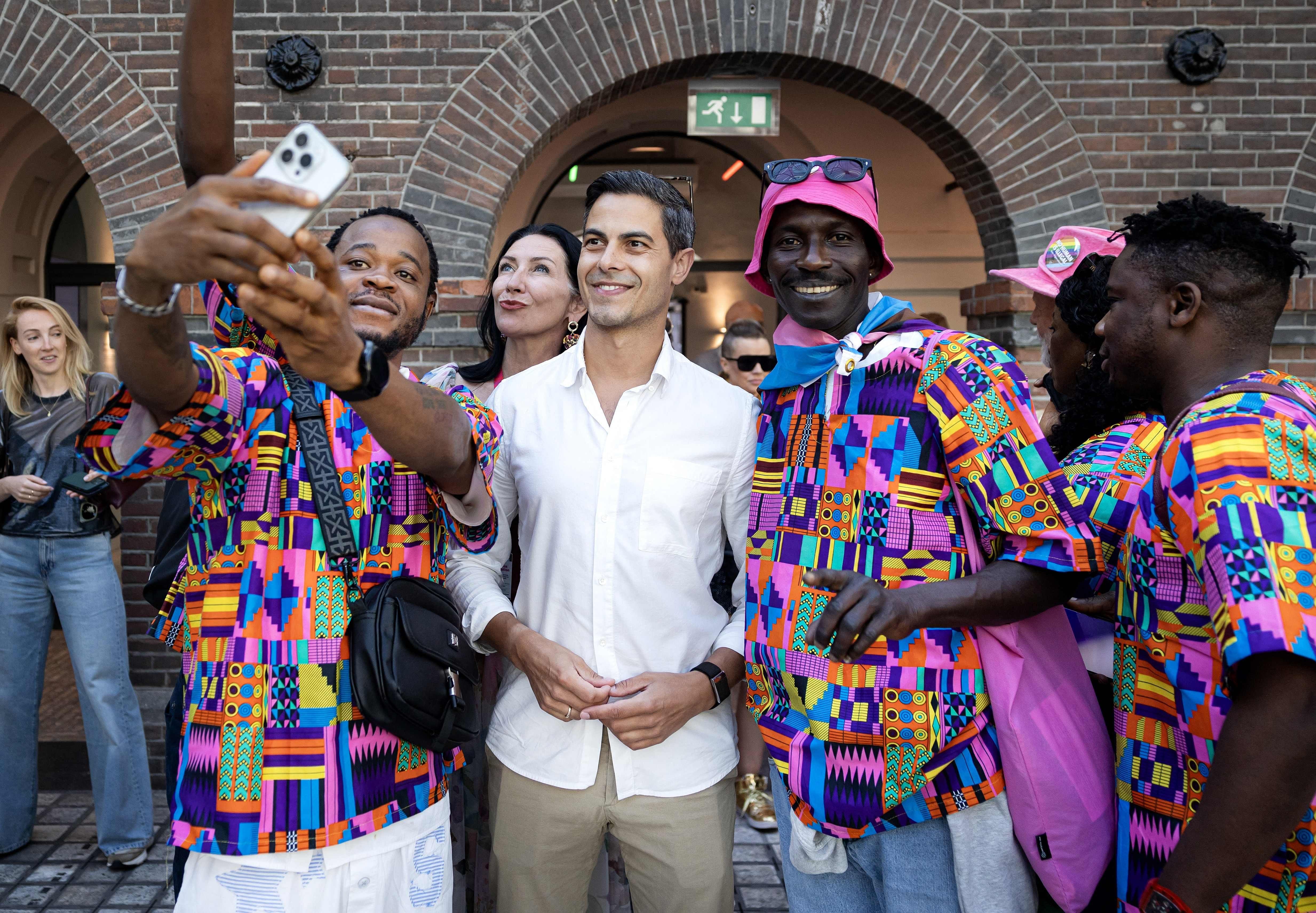 Mehrere Menschen machen gemeinsam ein Selfie bei einer Feier vor einem Backsteingebäude.
