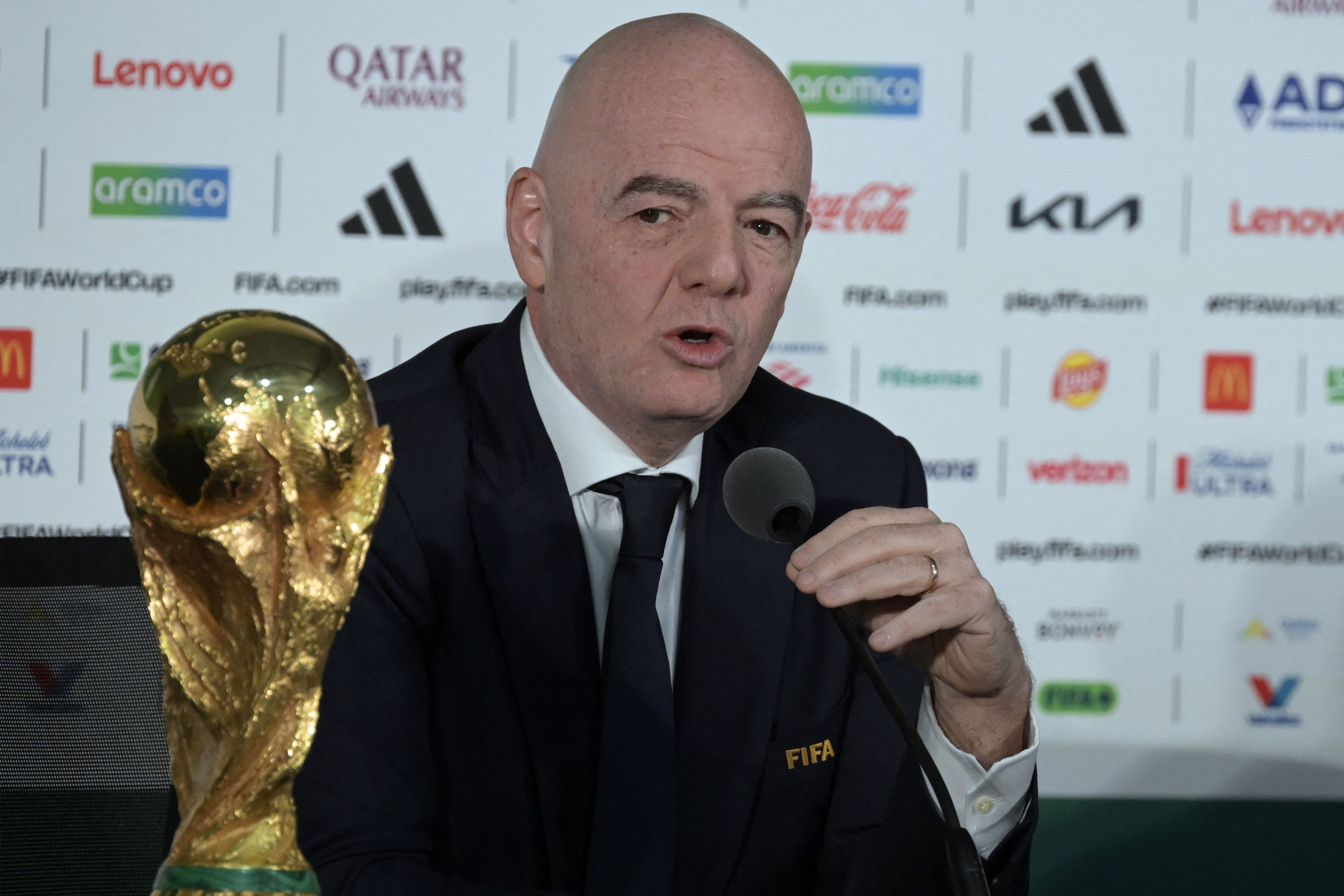 Ein Mann spricht bei einer Pressekonferenz neben dem FIFA-WM-Pokal und einem Mikrofon.