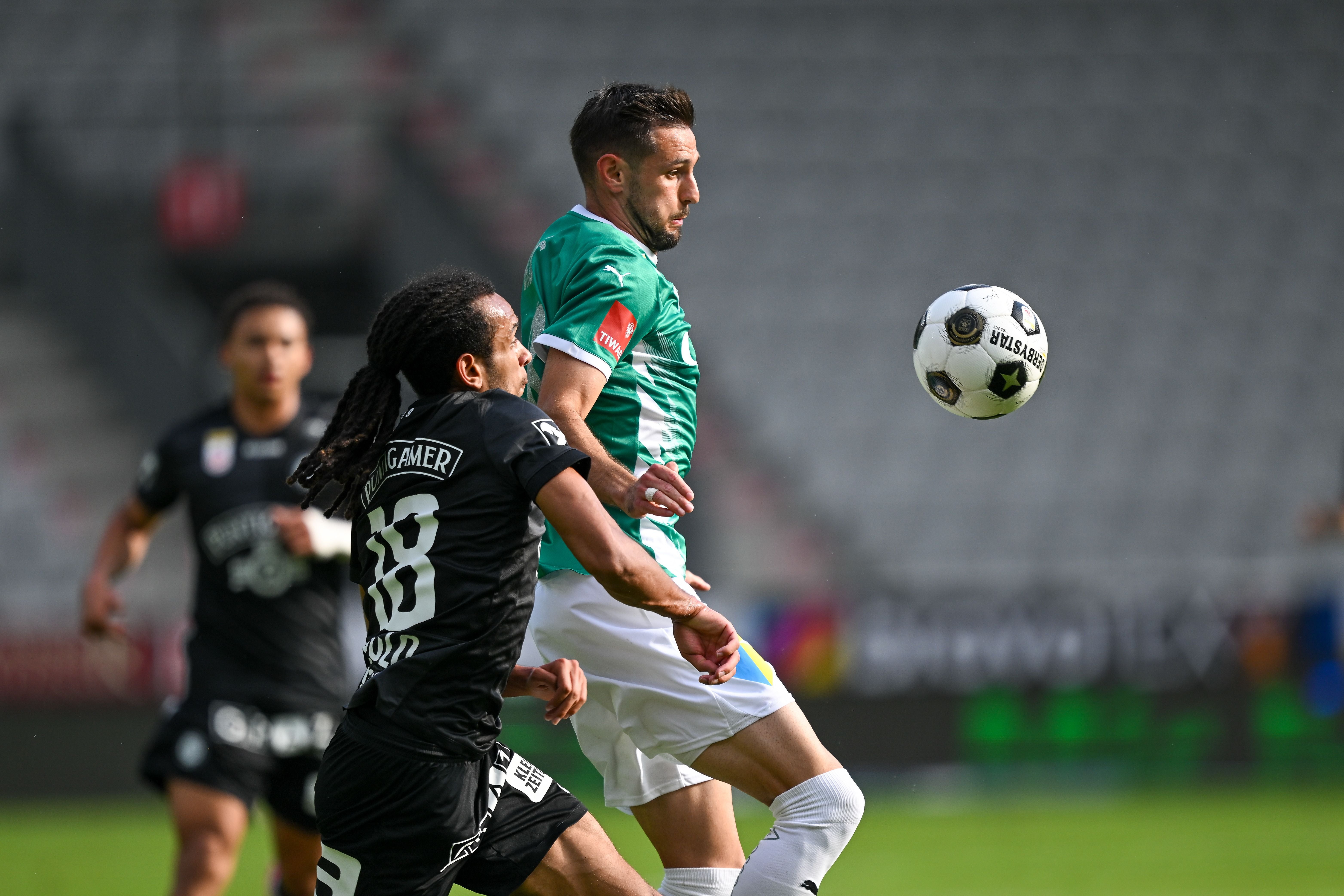 Zwei Fußballspieler kämpfen um den Ball während eines Spiels im Stadion.