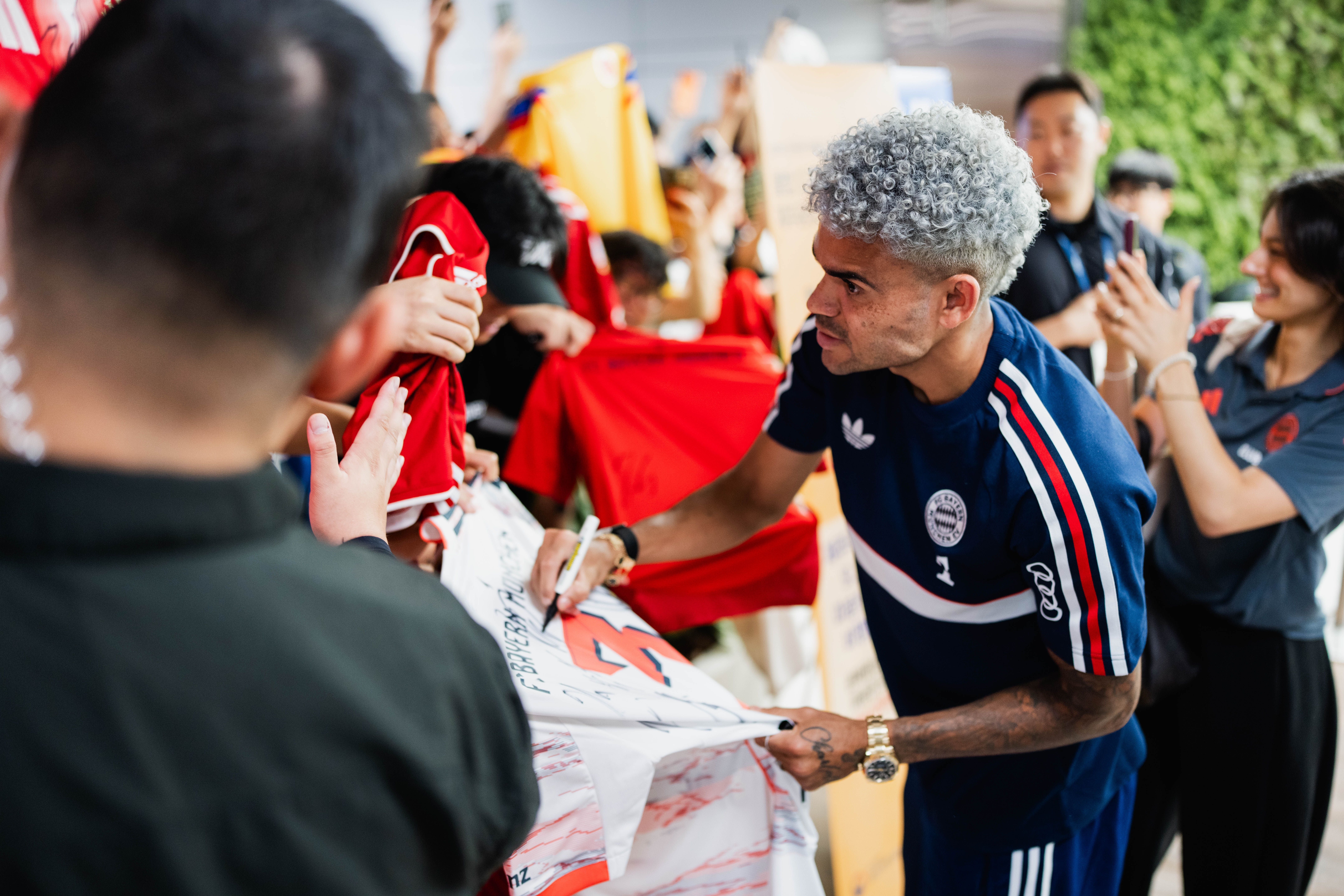Luis Díaz unterschreibt am Flughafen Jeju in Südkorea auf einem Trikot für begeisterte Fans.