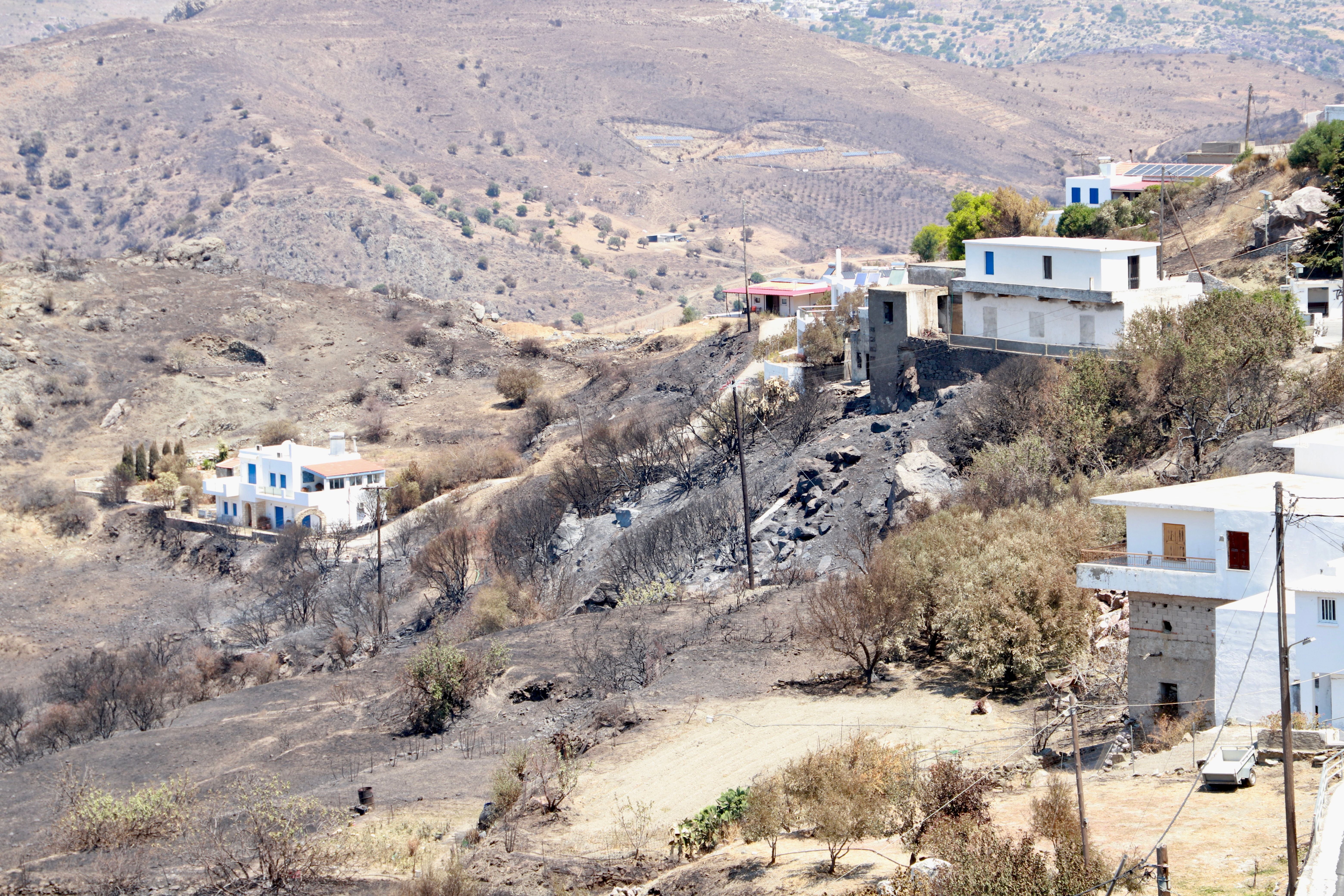 Verbrannte Landschaft mit einigen weißen Häusern nach einem Feuer nahe Rethymno, Kreta, Griechenland.
