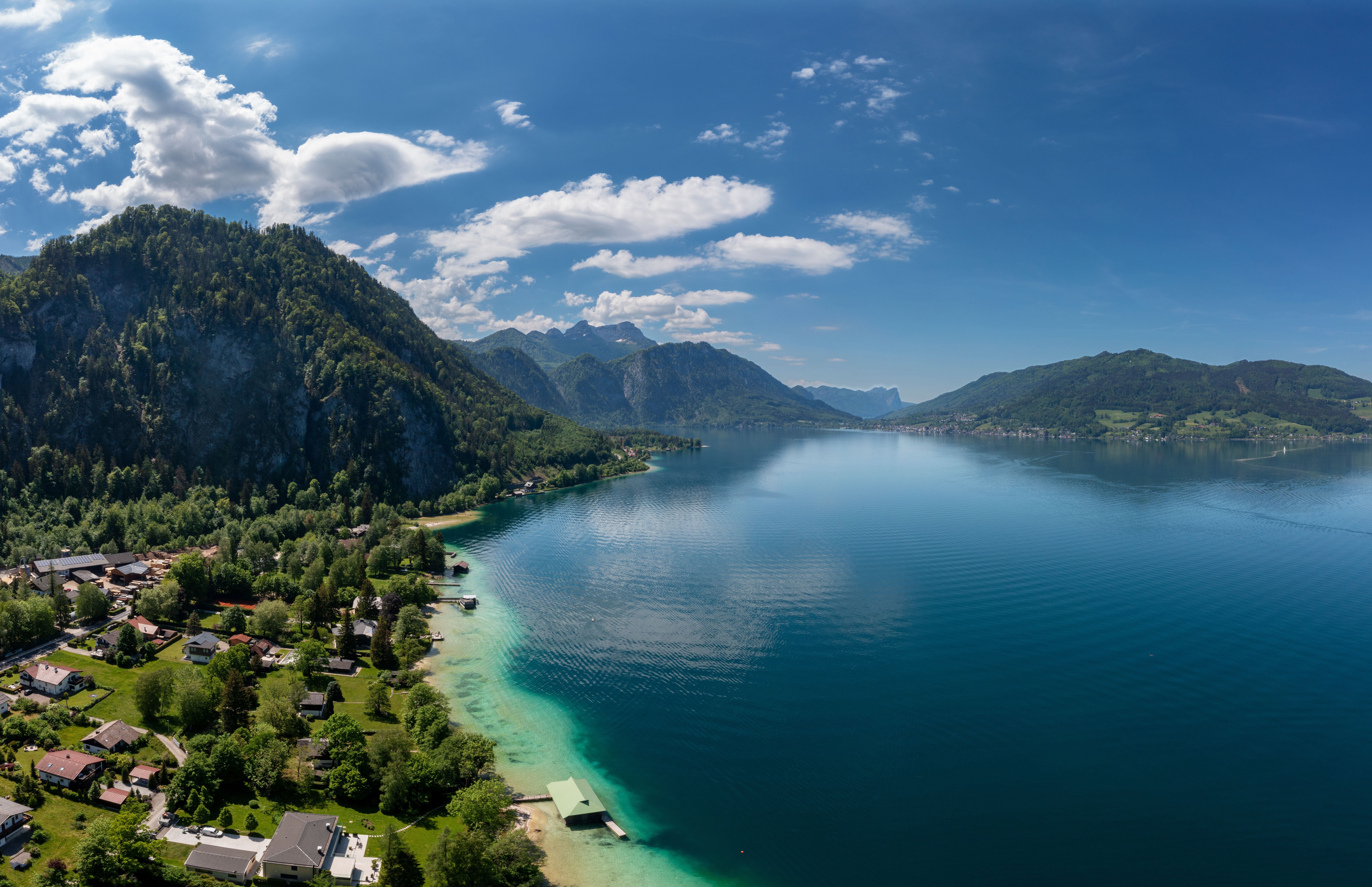 Luftaufnahme vom Attersee mit türkisblauem Wasser, Bergen und Häusern am Ufer.