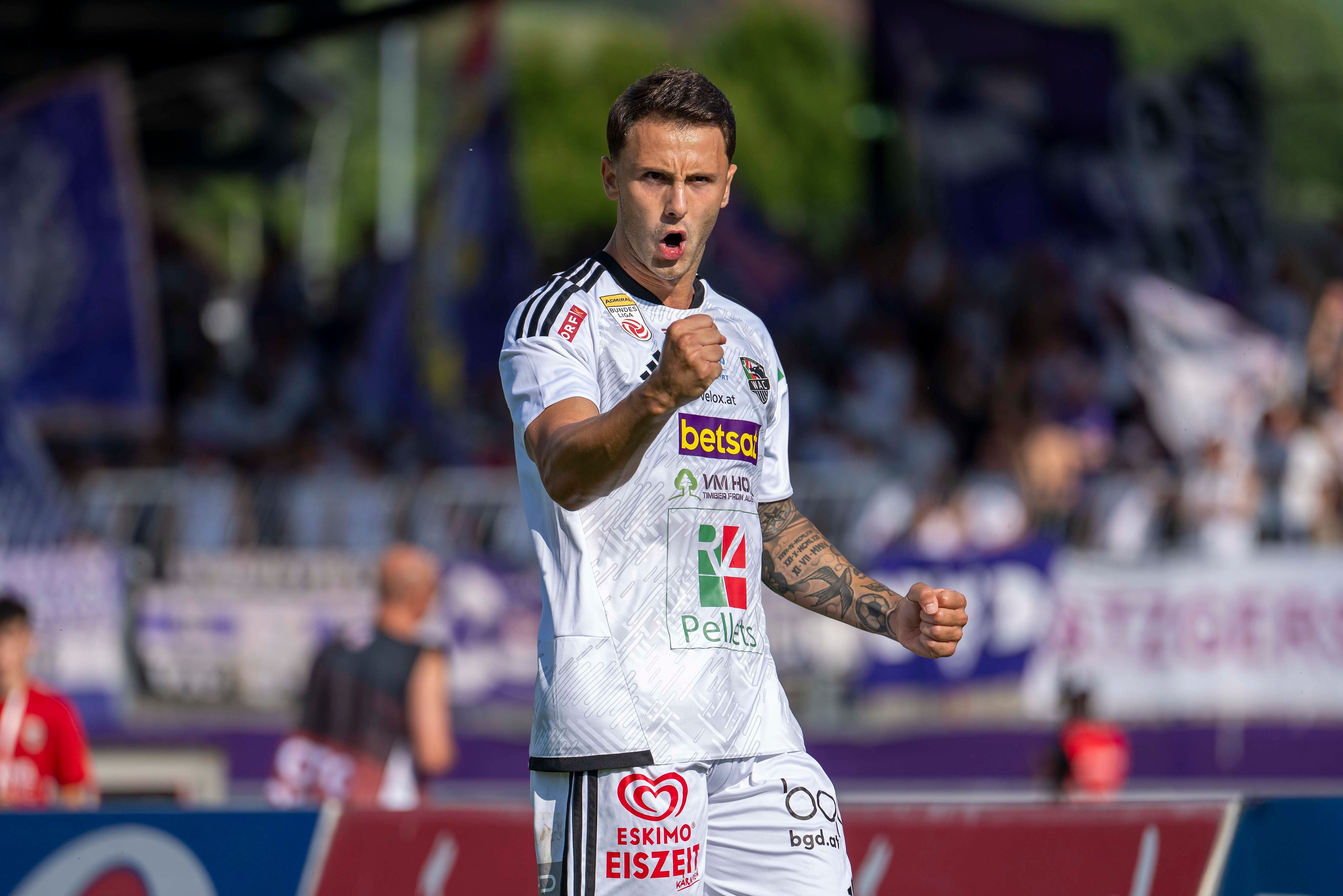 Ein Fußballspieler im weißen Trikot jubelt mit geballter Faust nach einem Tor.