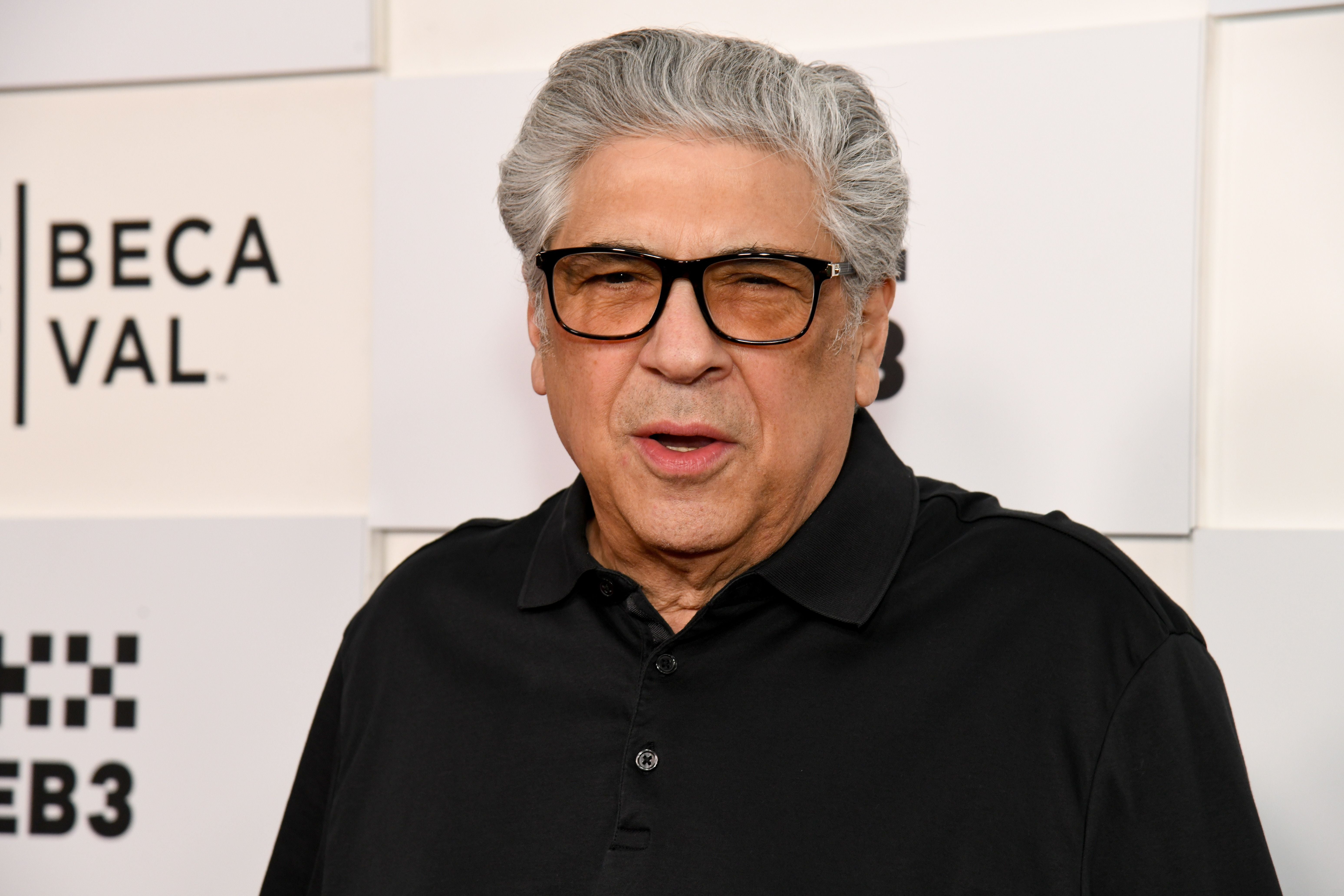 Ein älterer Mann mit grauen Haaren und Brille steht vor einer Wand mit Tribeca Festival-Logos.