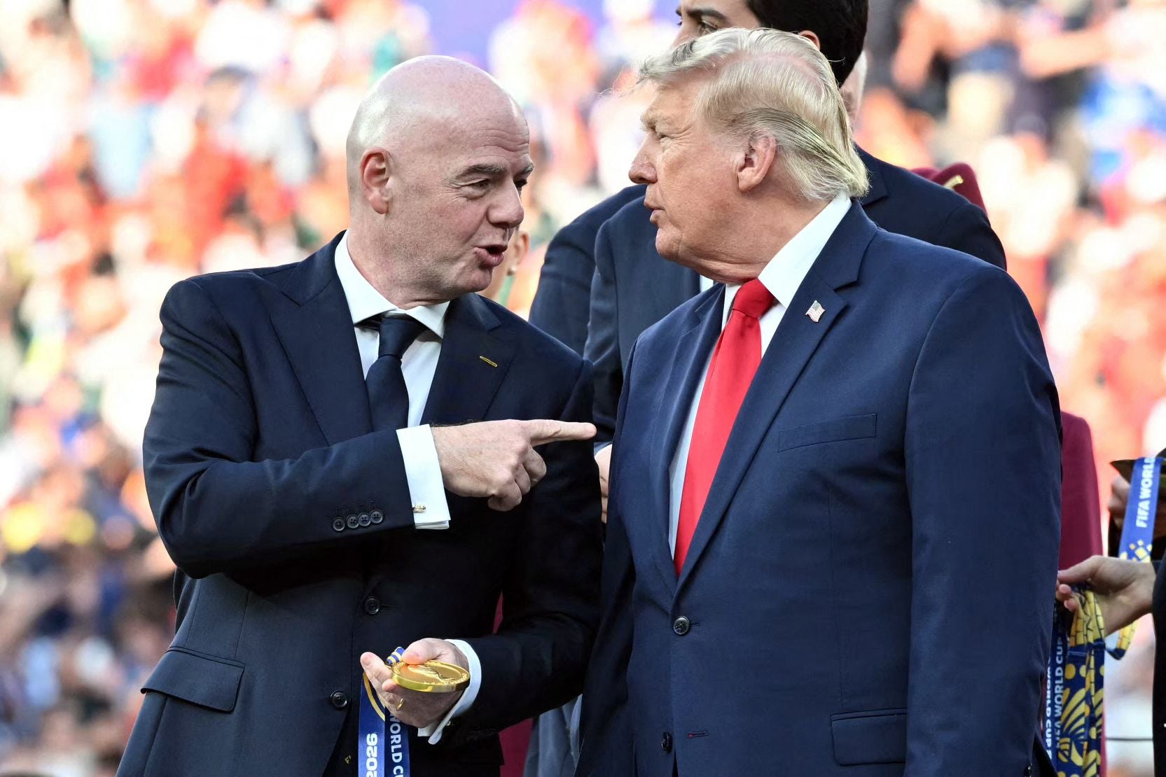 Zwei Männer im Anzug unterhalten sich bei einer Fußball-Siegerehrung im Stadion.