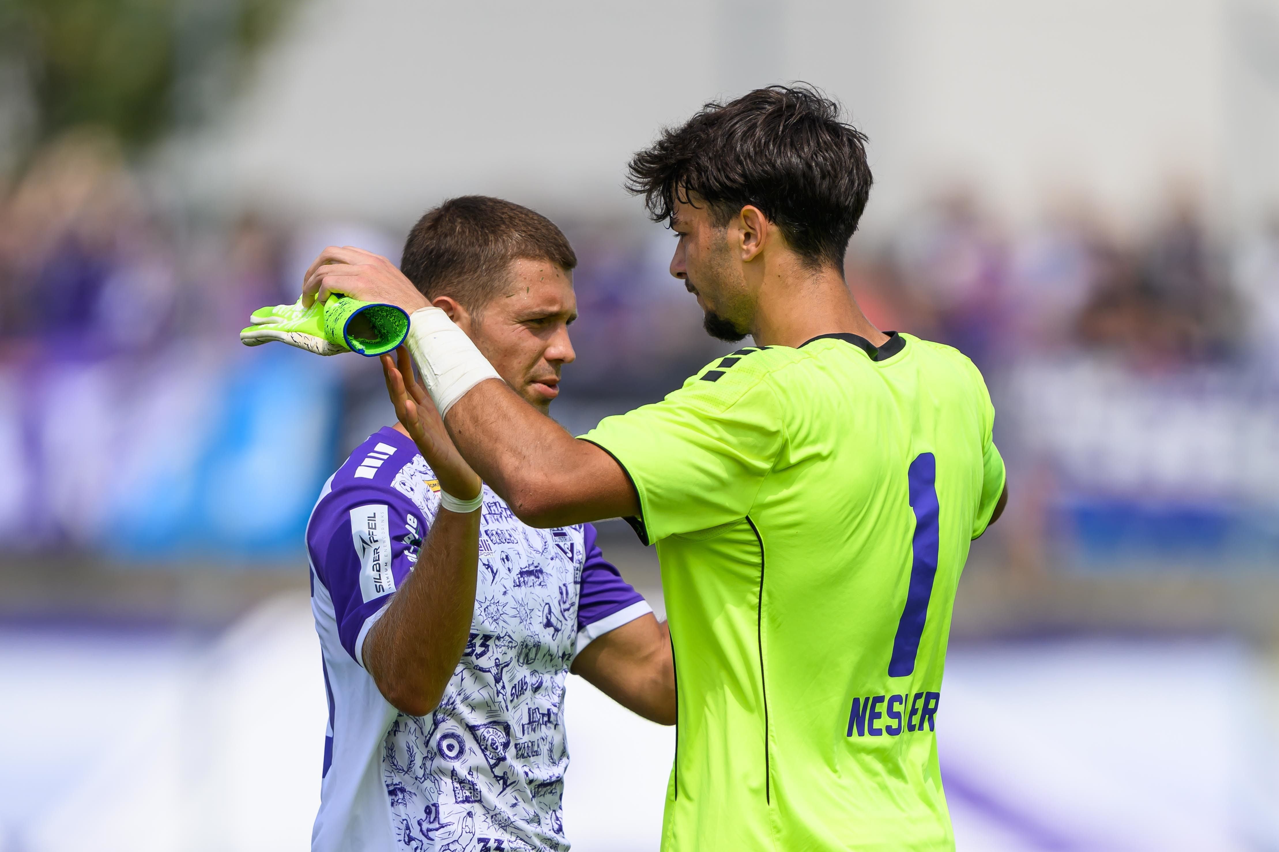 Zwei Fußballspieler umarmen sich nach einem Spiel und freuen sich.