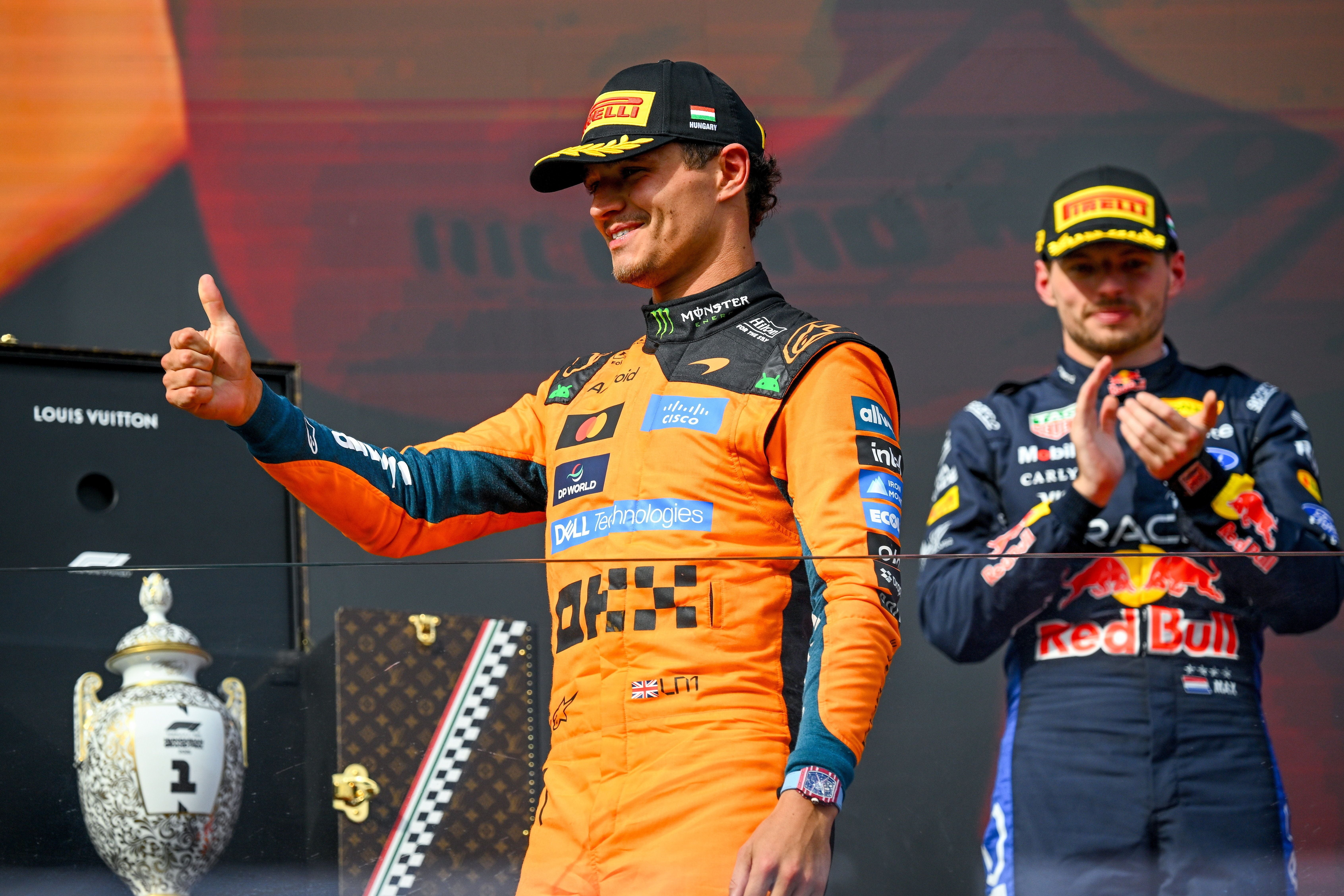 Lando Norris feiert auf dem Podium, während Max Verstappen applaudiert.