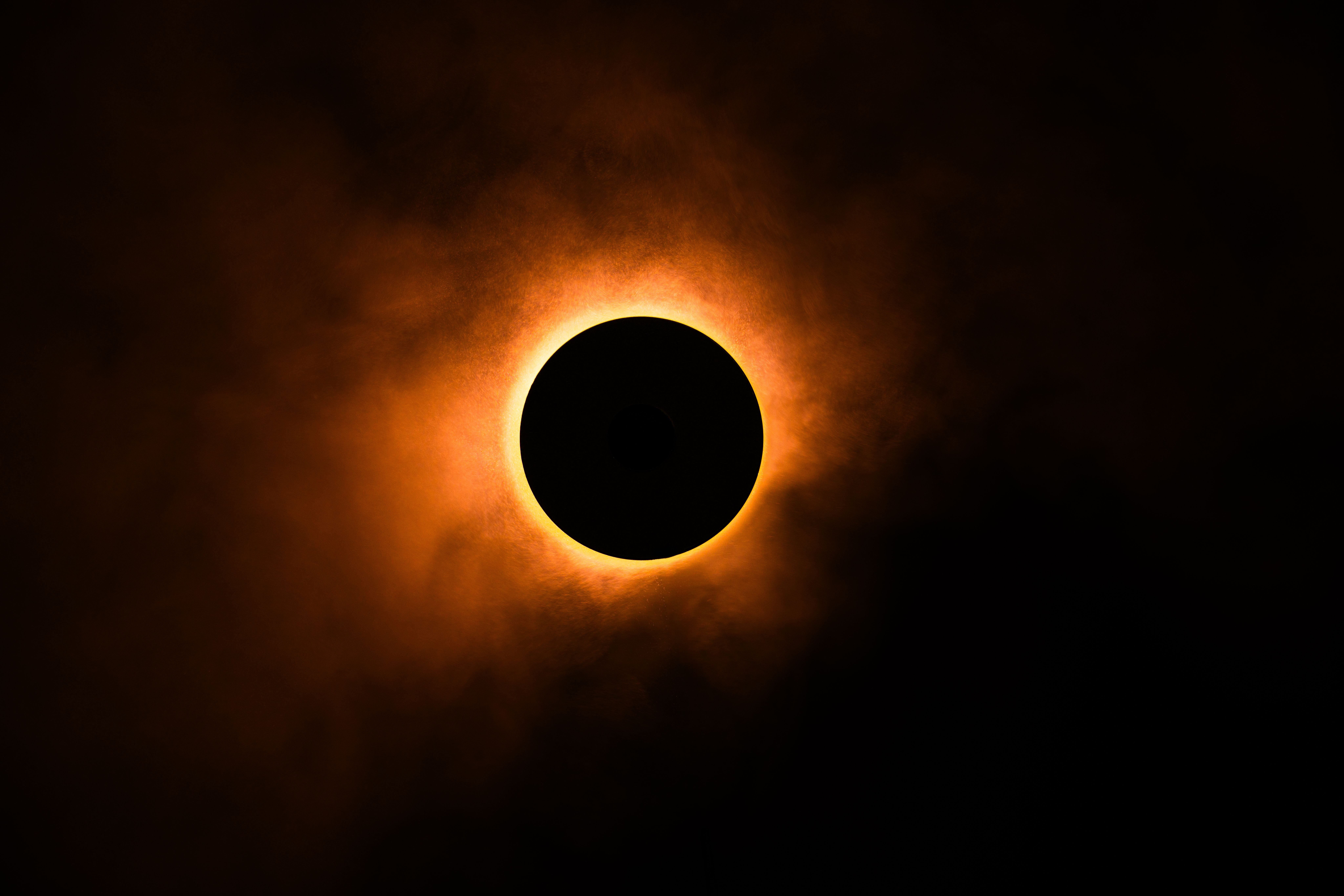 Eine Sonnenfinsternis mit leuchtendem Sonnenring und dunklem, wolkigem Himmel.