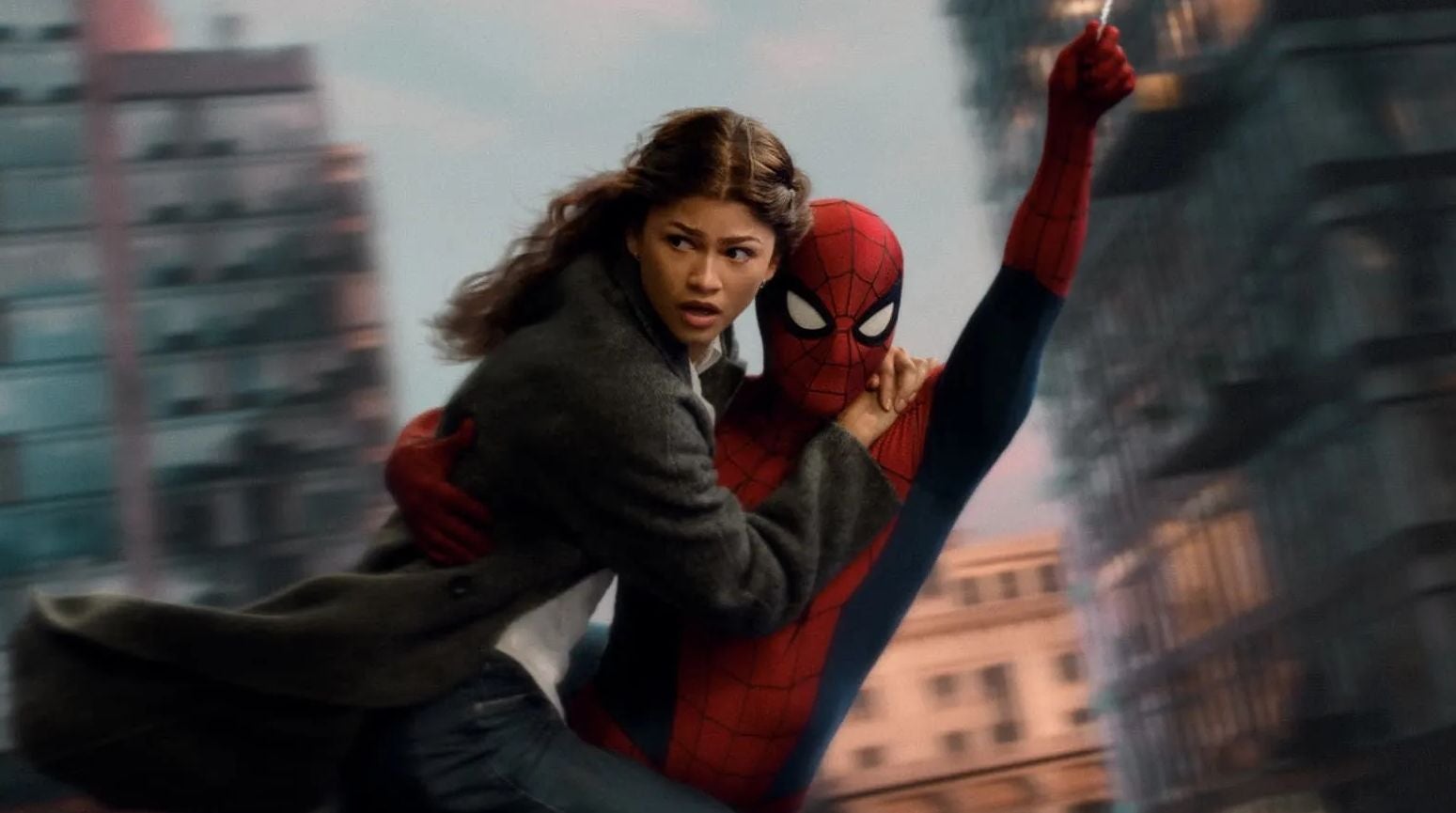 Spider-Man schwingt mit einer Frau durch eine Stadt zwischen verschwommenen Hochhäusern.