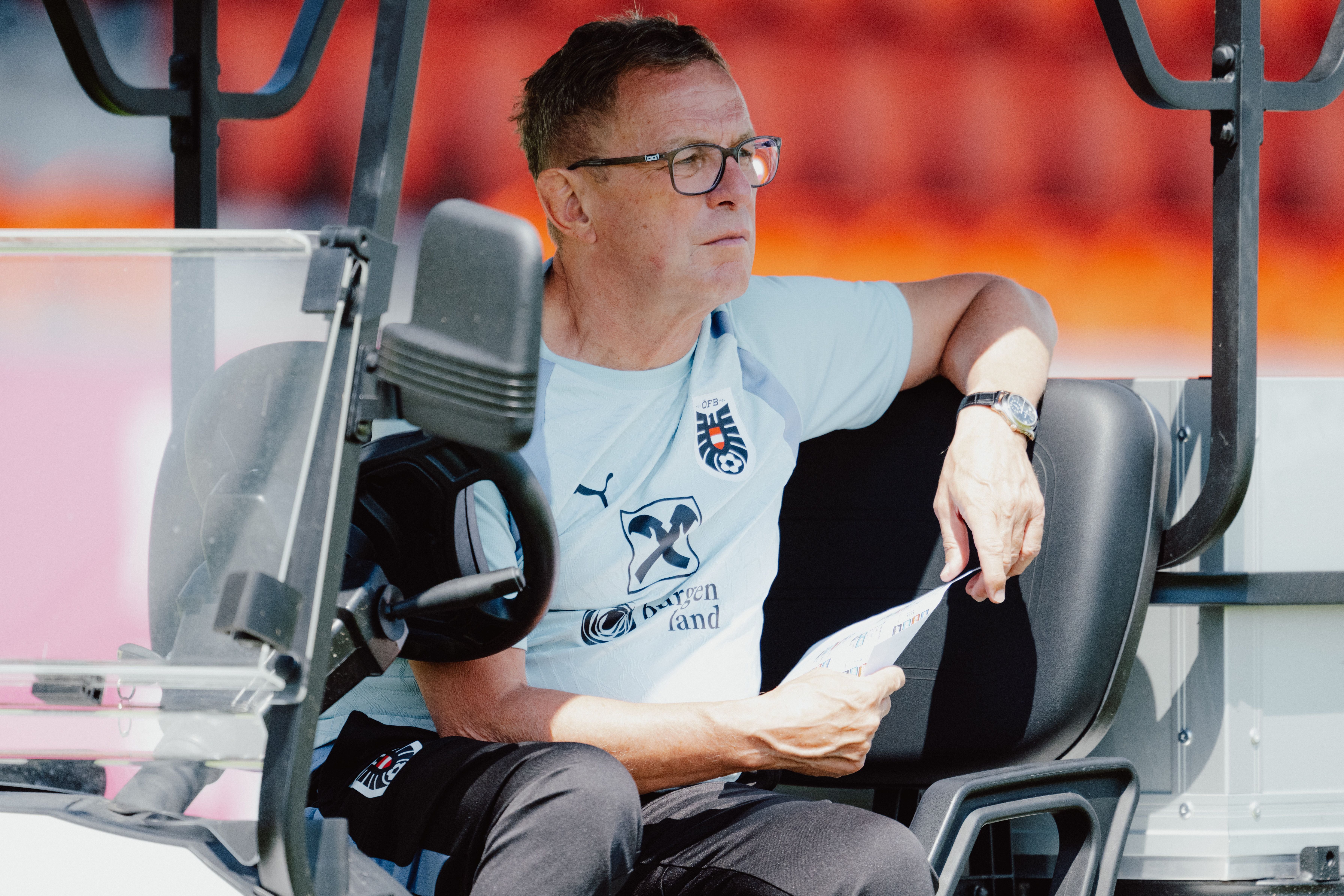 Ein Mann im Trainingsanzug sitzt auf einem Golfcart und schaut nachdenklich nach vorne.