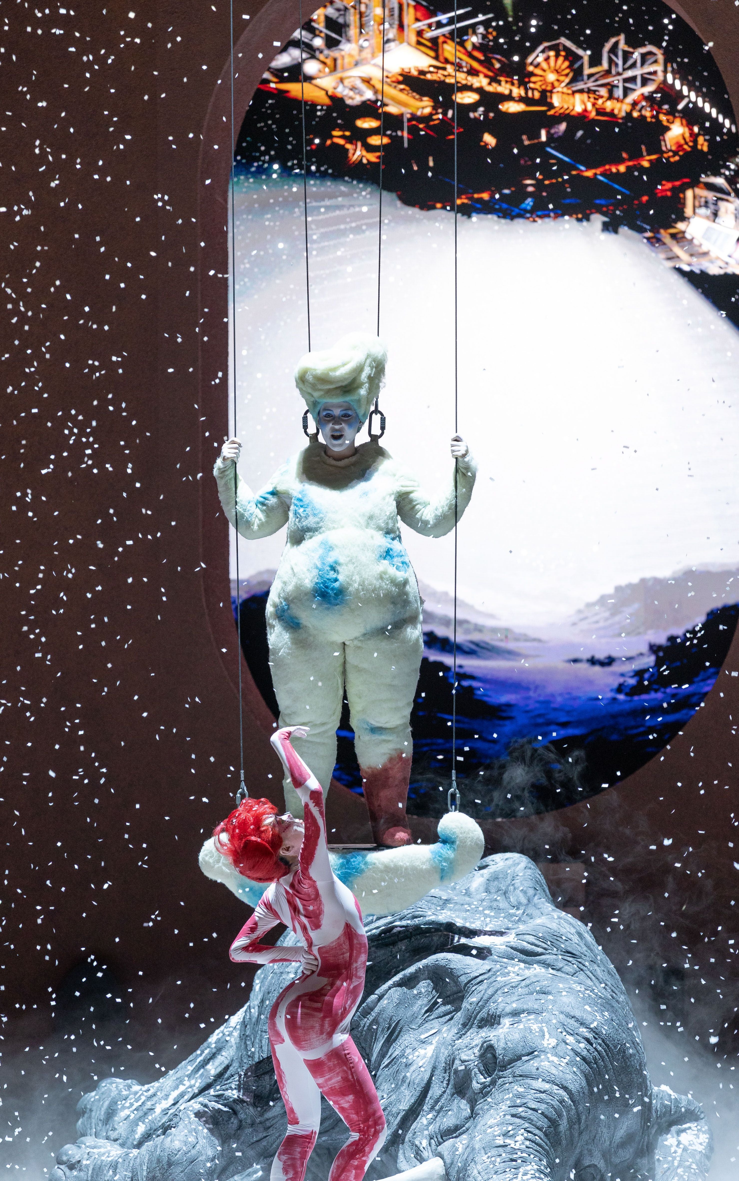 Zwei Künstlerinnen in fantasievollen Kostümen auf einer Bühne mit künstlichem Schnee.