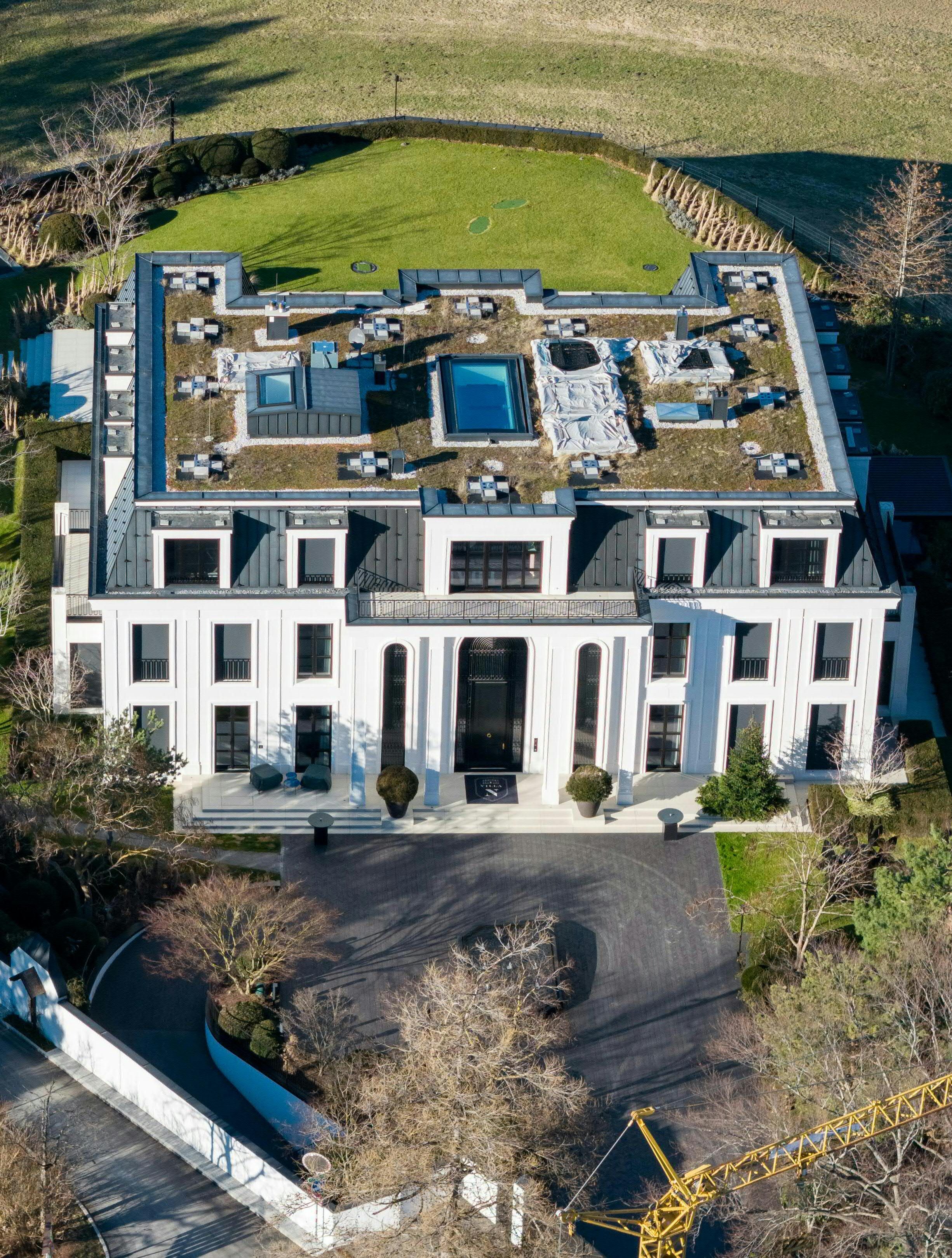 Luftaufnahme einer großen weißen Villa mit Flachdach, Garten und Einfahrt in Innsbruck.