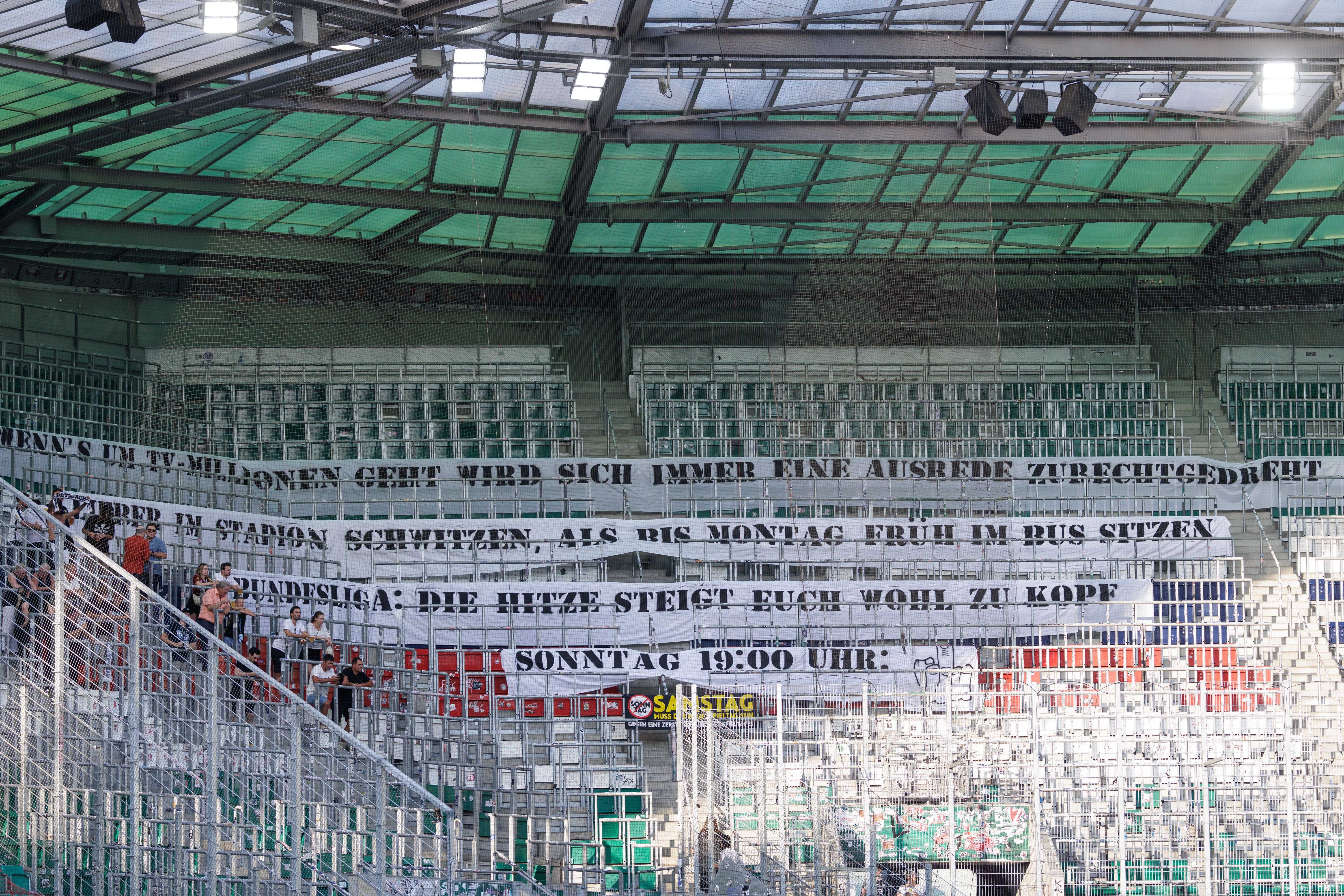 Mehrere Altach-Fans stehen in einem leeren Stadionblock mit großen Protestbannern.
