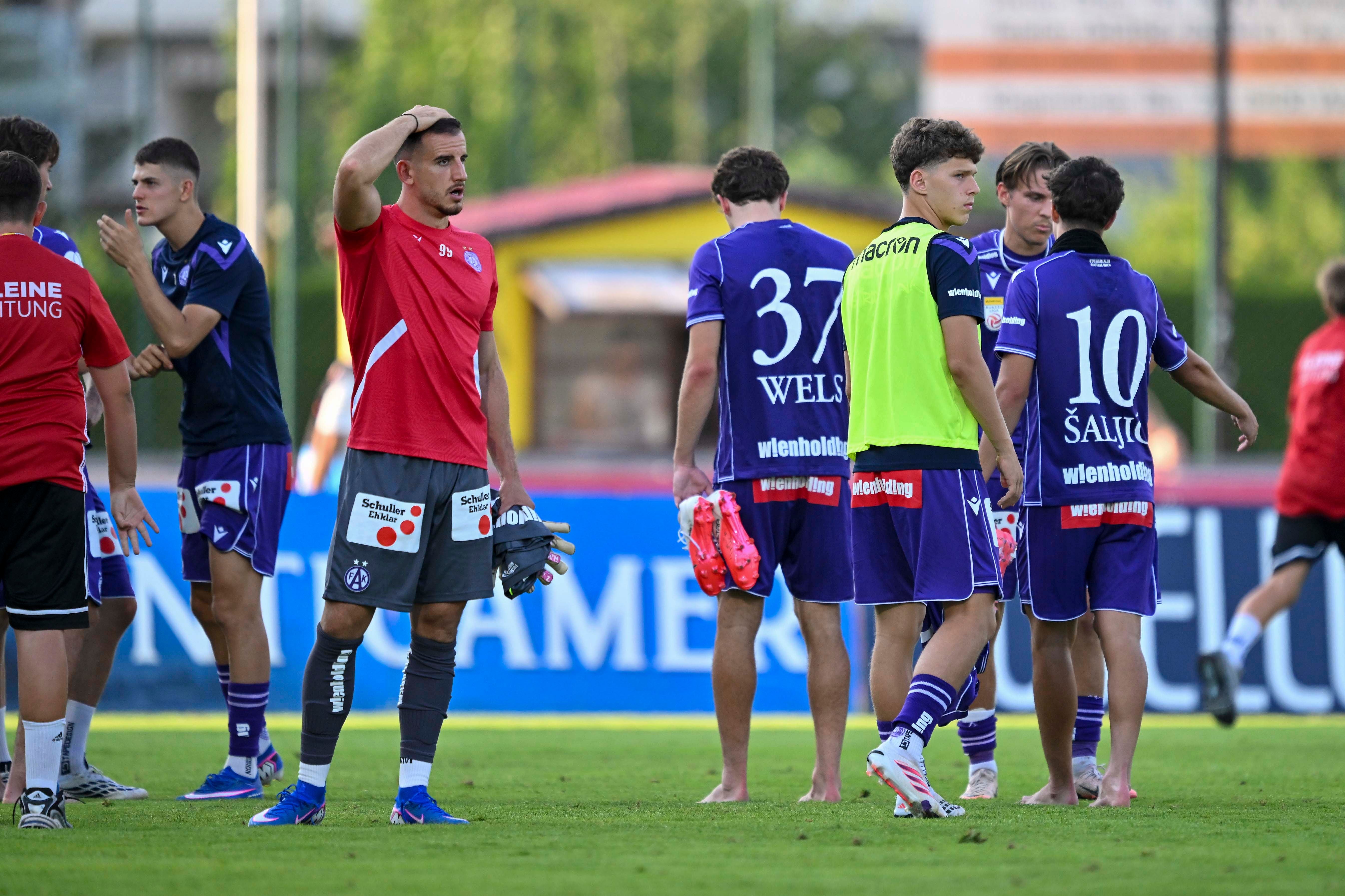 Fußballspieler von Austria Wien wirken nach dem Spiel enttäuscht und stehen auf dem Spielfeld.