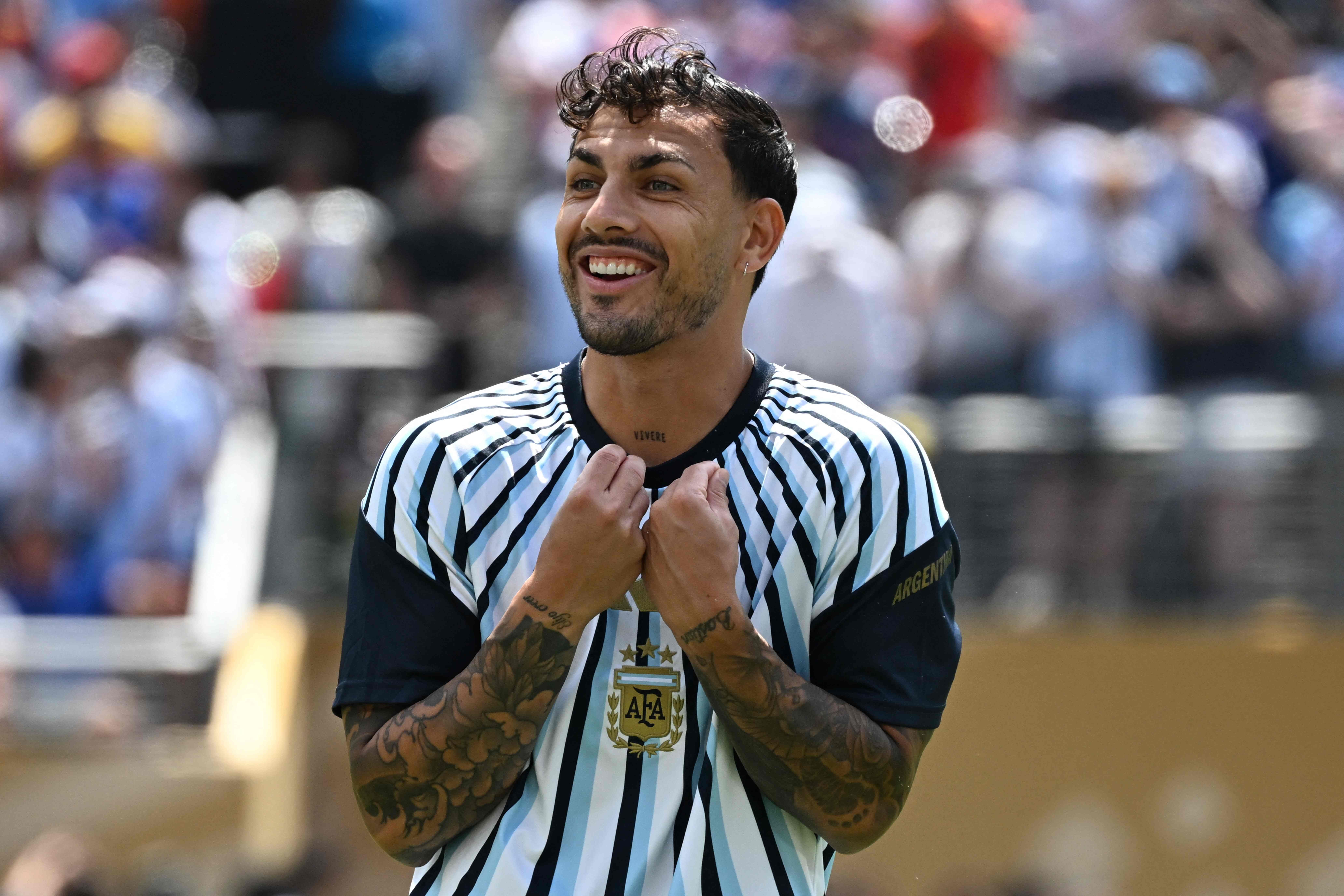 Ein argentinischer Fußballspieler lächelt im gestreiften Trikot auf dem Spielfeld.