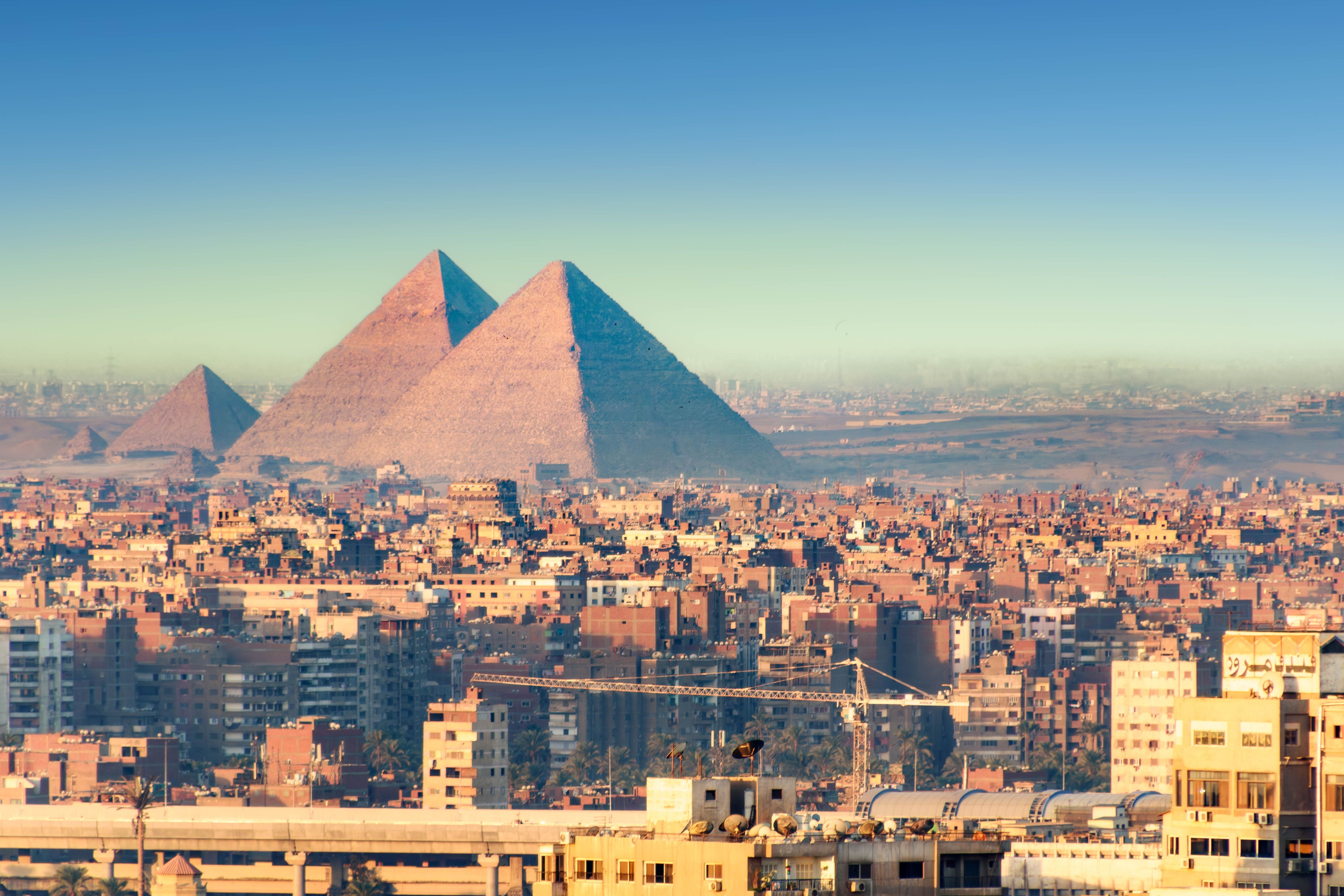 Panoramablick über Kairo mit den großen Pyramiden im Hintergrund bei klarem Himmel.