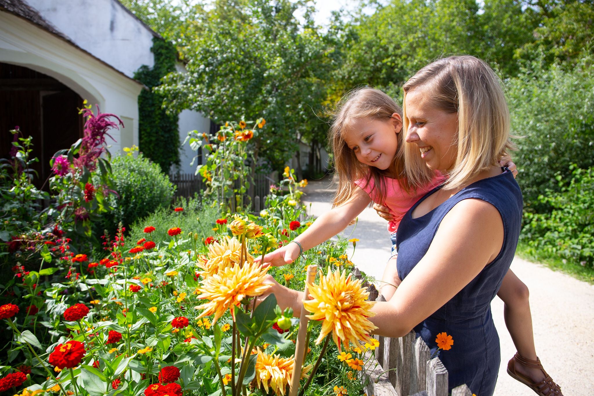 Frau und Kind betrachten bunte Blumen im Garten des Museumsdorfs Niedersulz.