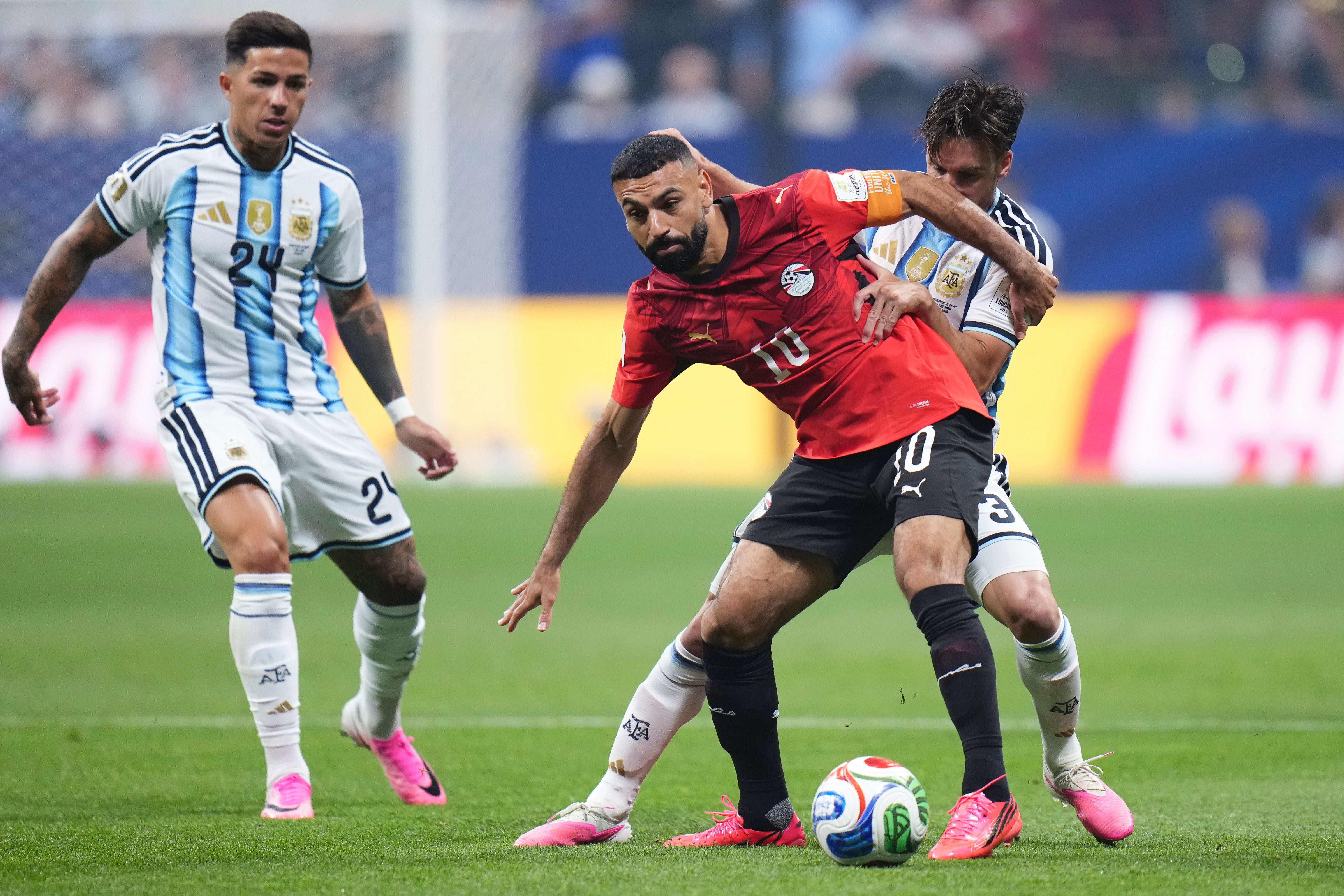 Ein ägyptischer und zwei argentinische Fußballspieler kämpfen um den Ball im Spiel.