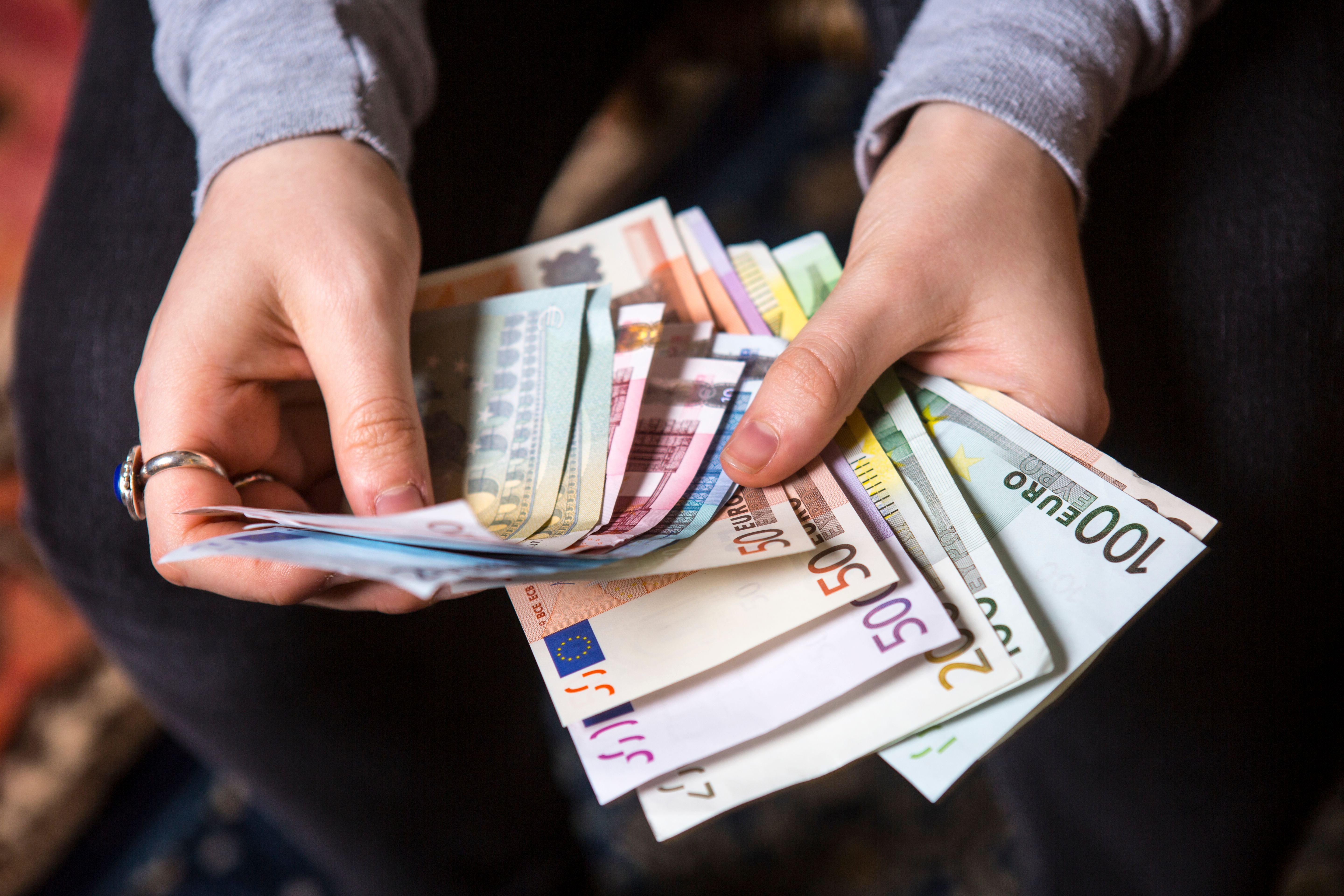 Frau hält verschiedene Euro-Geldscheine, einschließlich eines 500-Euro-Scheins, in den Händen.