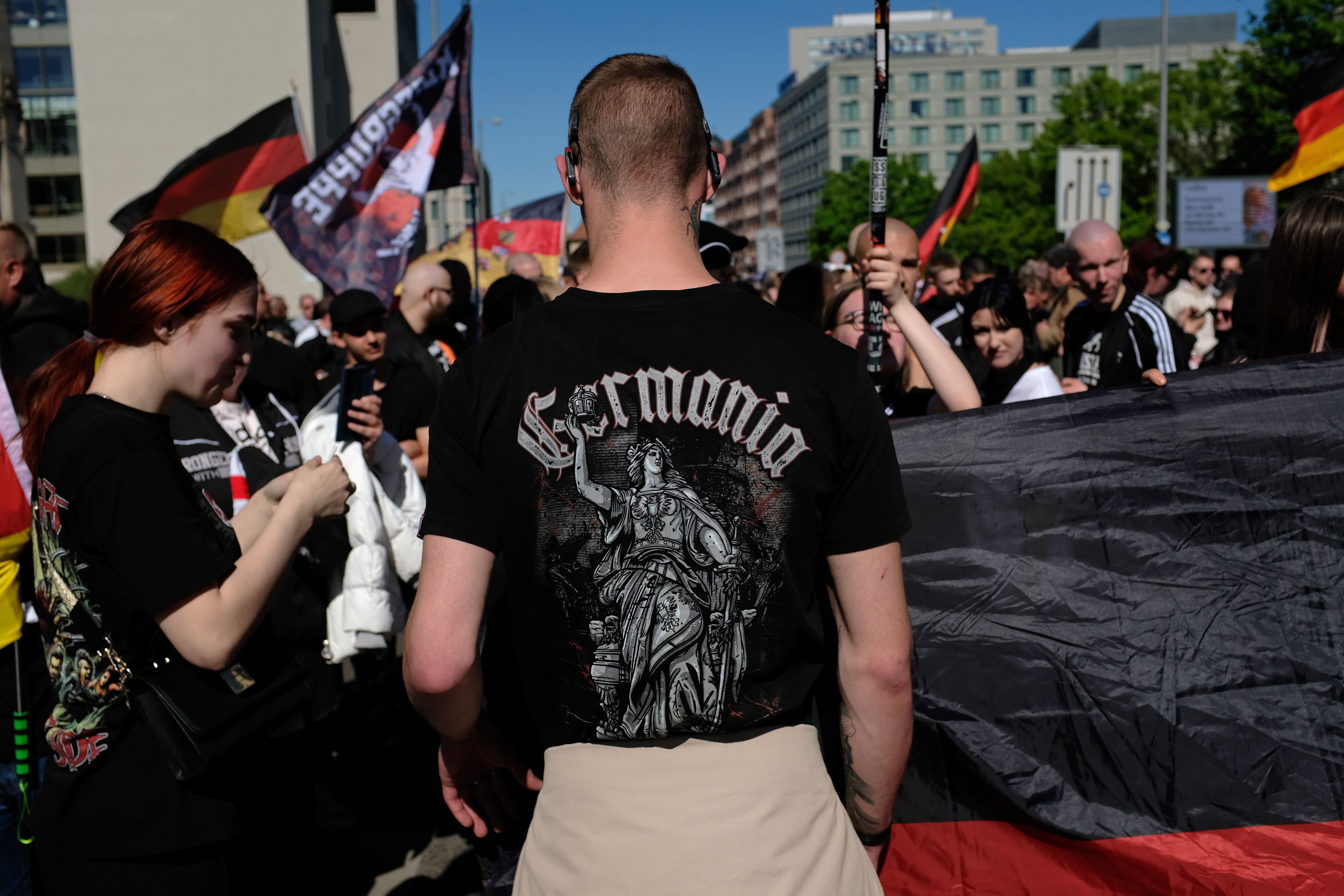 Junge Menschen bei einer Demonstration mit Deutschlandfahnen, einer trägt ein „Germania“-T-Shirt.