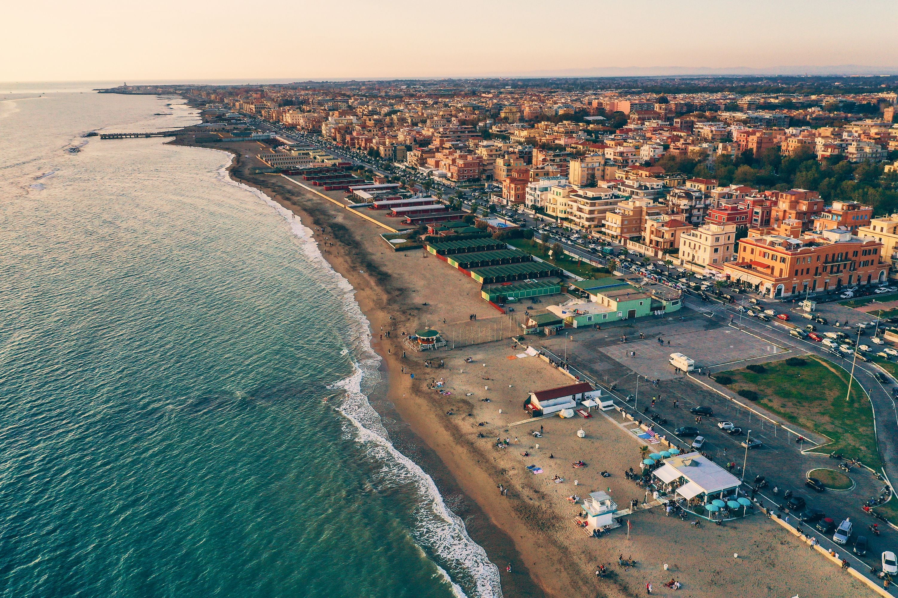 Luftaufnahme des Strandes von Ostia bei Rom mit Meer und Stadt im Sonnenlicht.