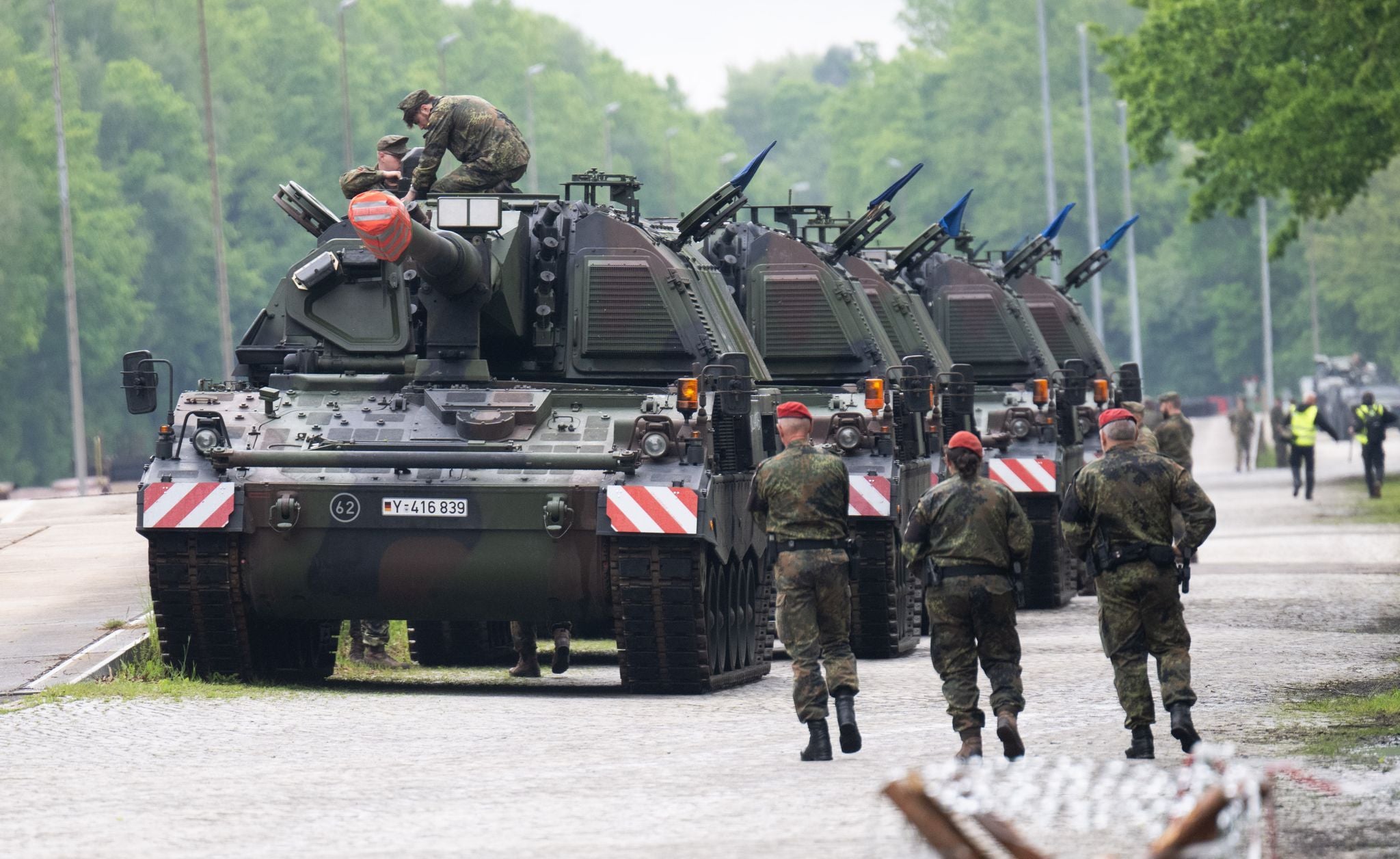 Soldaten neben mehreren Panzerhaubitzen bei einer Militärübung auf einem Truppenübungsplatz.