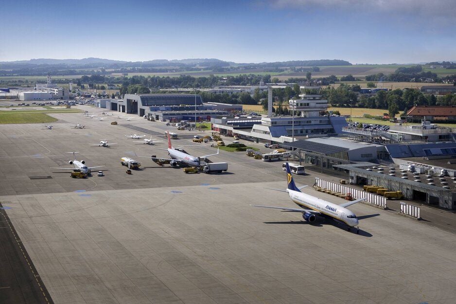 Flugzeuge stehen auf dem Vorfeld des Linzer Flughafens, im Hintergrund das Flughafengebäude.