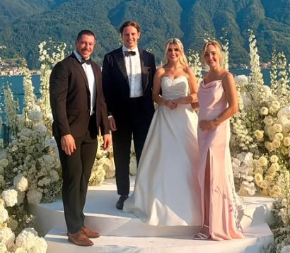 Vier elegant gekleidete Personen stehen auf einer blumengeschmückten Hochzeitstreppe im Freien.