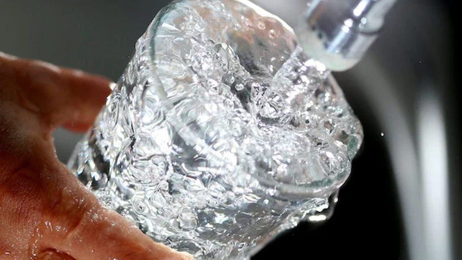 Ein Glas wird unter einem Wasserhahn mit Leitungswasser gefüllt.