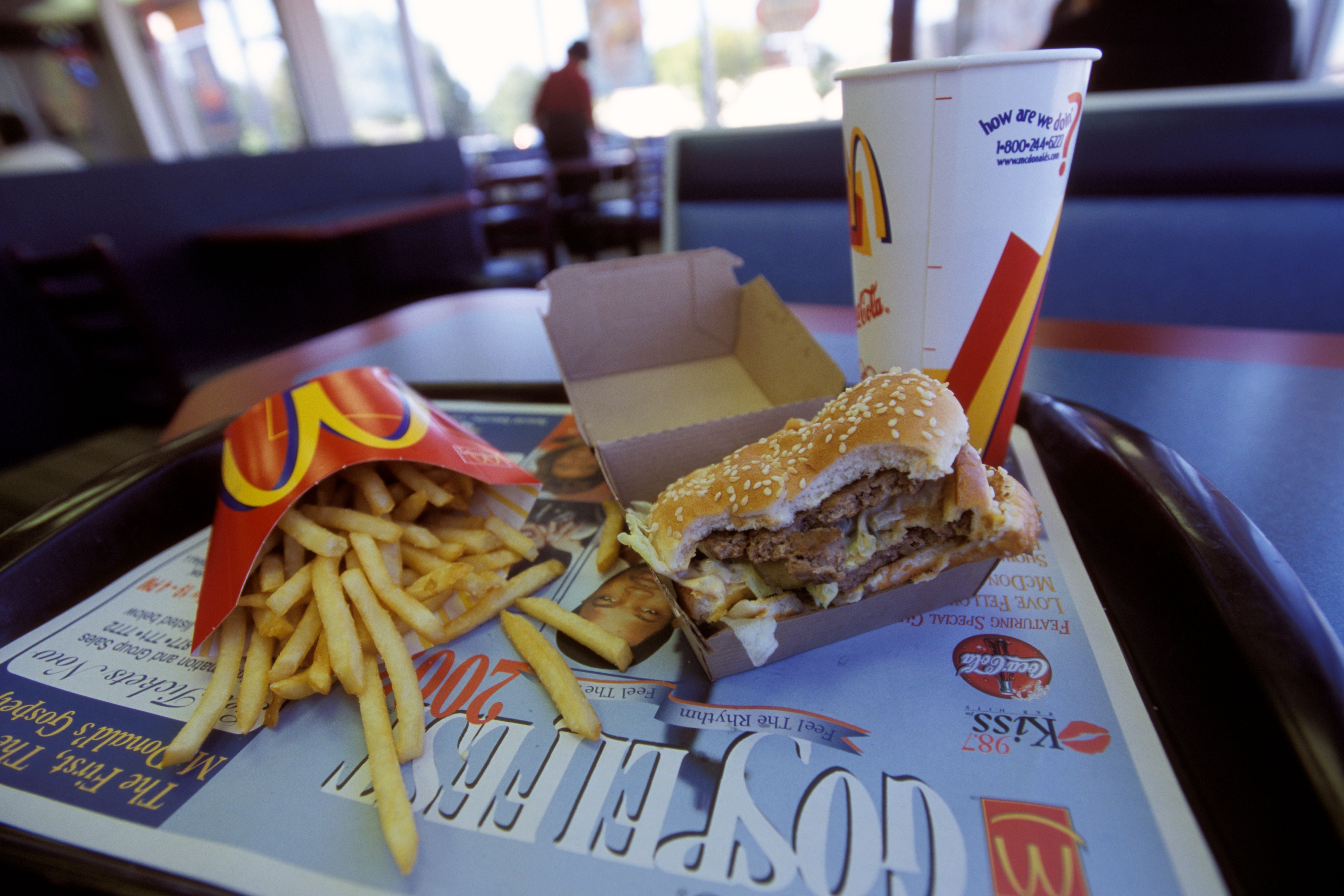 Tablett mit Pommes, angebissenem Burger und Softdrink in einem McDonald's Restaurant.