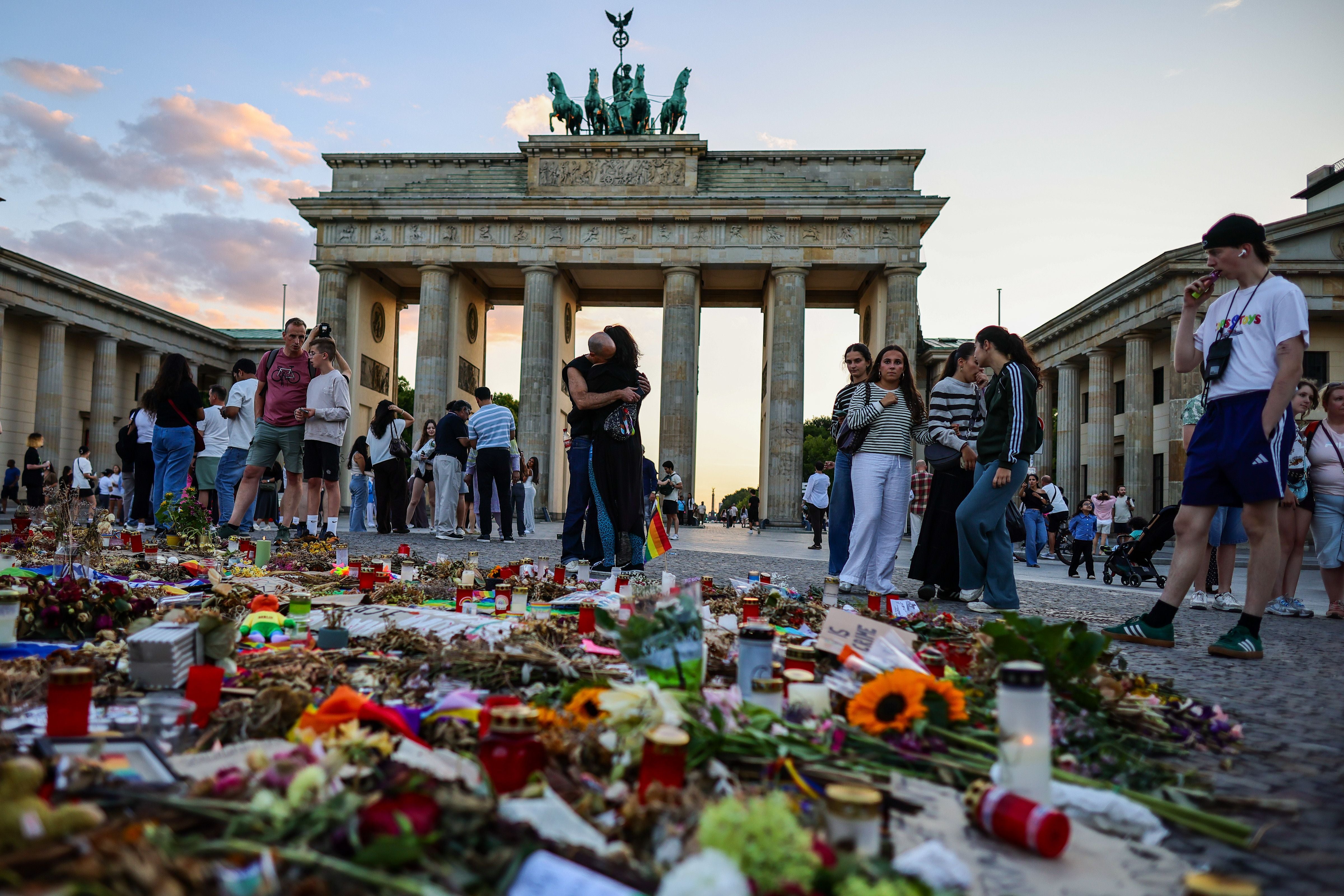 Menschen gedenken mit Blumen und Kerzen an einem Mahnmal vor dem Brandenburger Tor in Berlin.