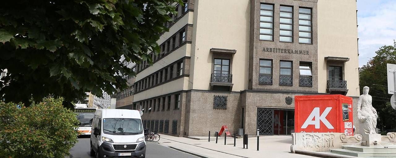Gebäude der Arbeiterkammer Oberösterreich mit Statue und rotem AK-Würfel vorne.