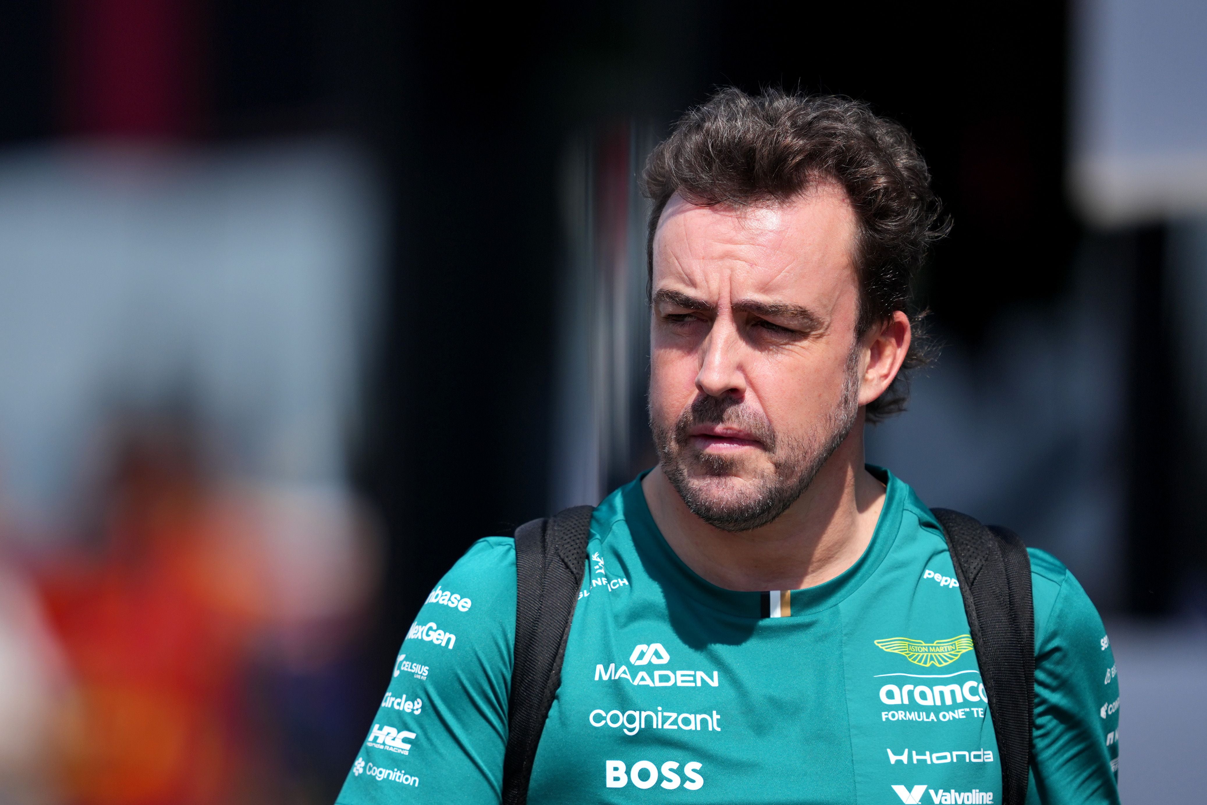 Ein Mann im grünen Aston Martin F1 Team-Shirt geht mit ernstem Blick und Rucksack im Freien.