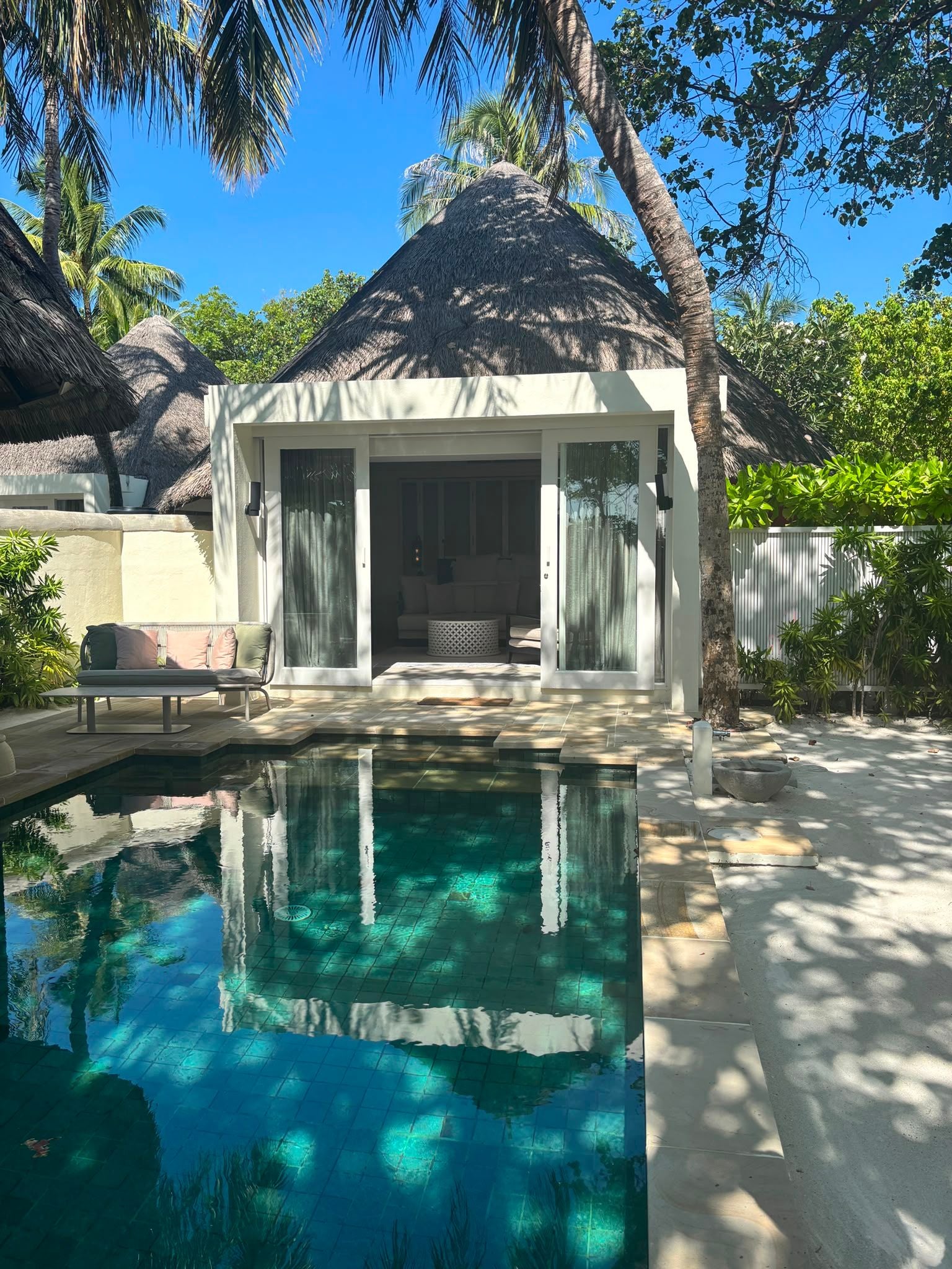 Strandvilla mit privatem Pool, umgeben von Palmen und tropischer Vegetation.