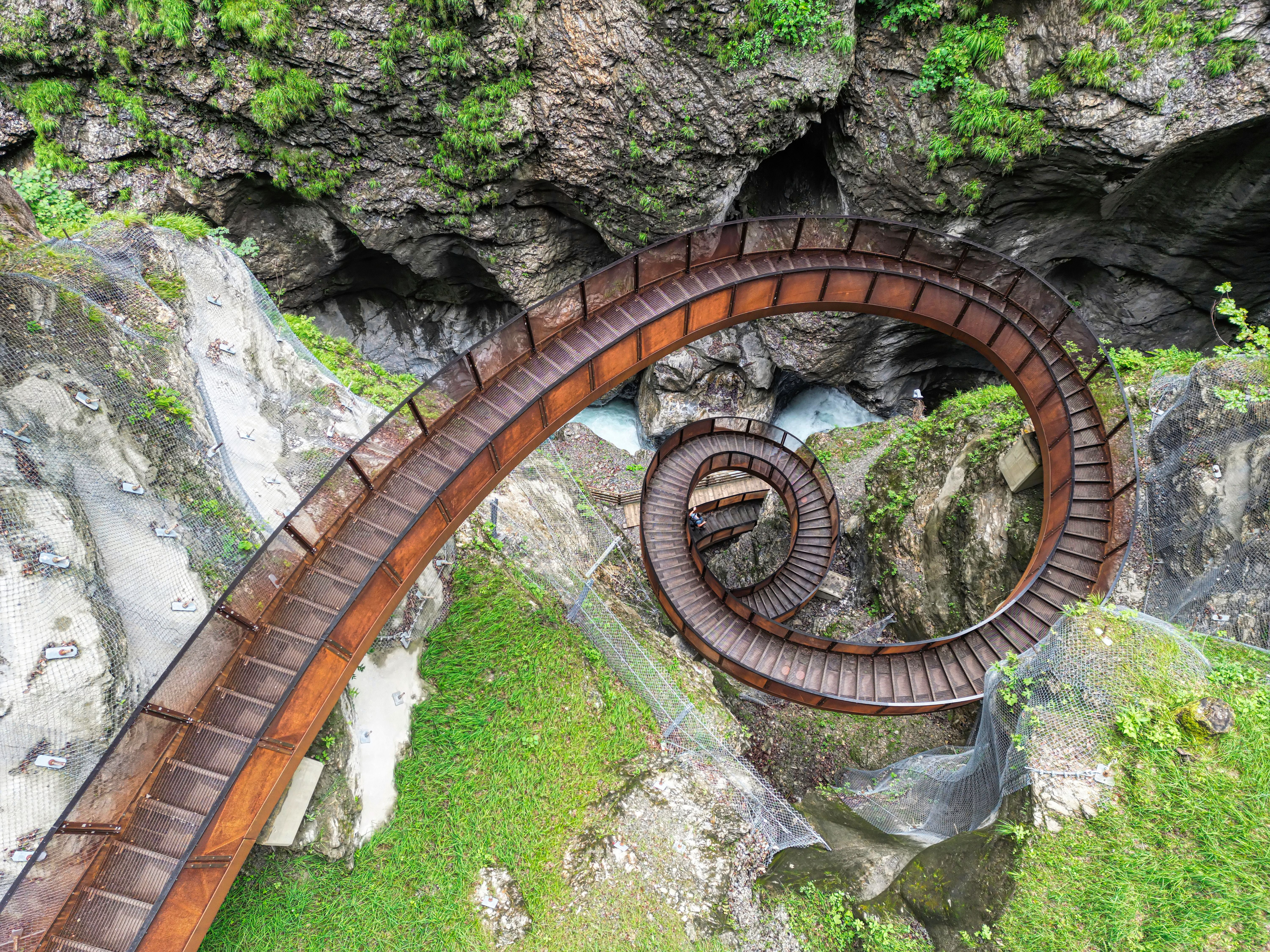 Spiralförmige Metalltreppe namens Helix in der Liechtensteinklamm, umgeben von Felsen und Grün.