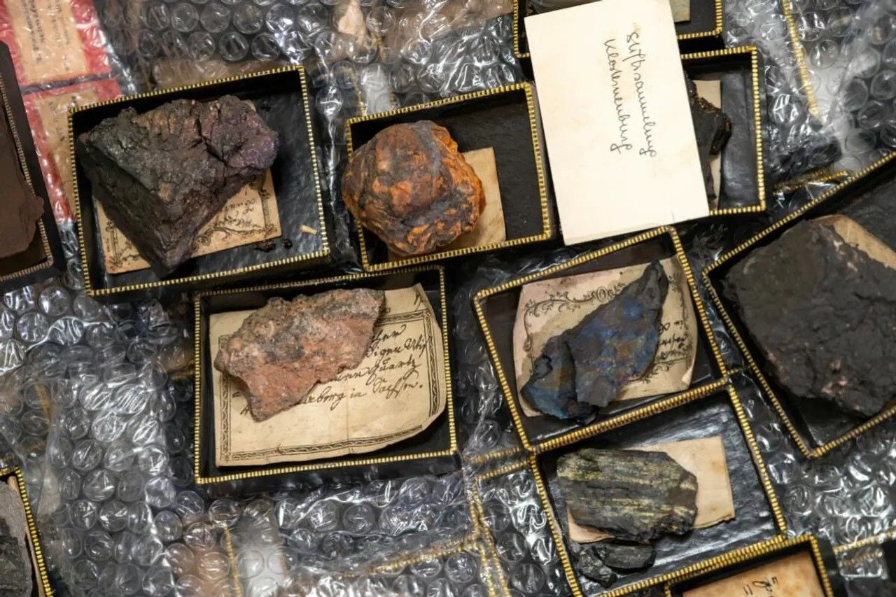 Mehrere verschiedene Gesteinsproben in kleinen Kästchen mit handschriftlichen Etiketten.