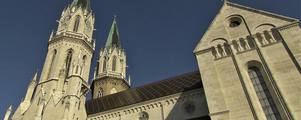 Das Stift Klosterneuburg mit markanten Türmen und romanischer Fassade vor blauem Himmel.